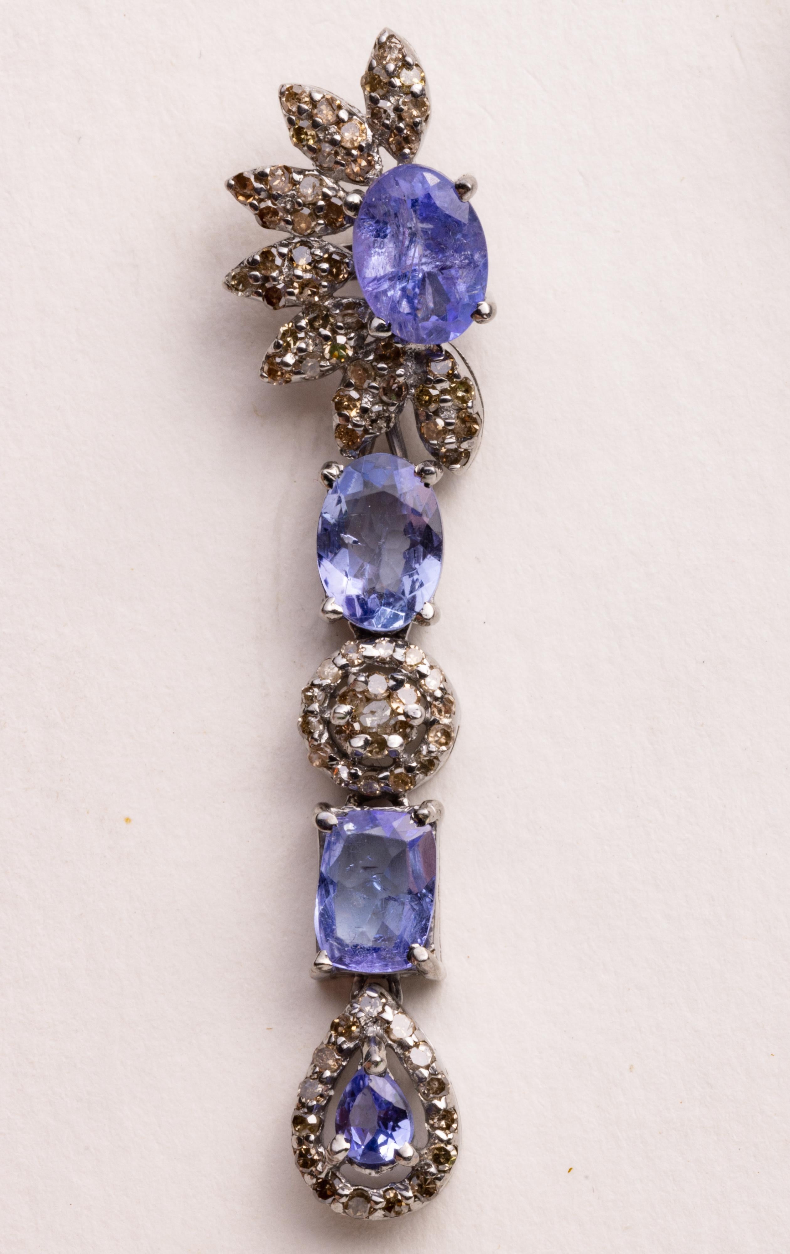 Unusual dangle earrings featuring oval and pear-shaped faceted Tanzanite gemstones with round, brilliant cut diamonds in a pave` setting.  Sterling silver with 18K gold post for pierced ears.  carat weight of diamonds totals 1.12, Tanzanite gems