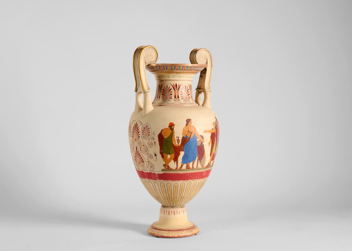 This cream colored urn is illustrated with mythological figurative scenes along with finely detailed patterning and gilded edges. Signed.