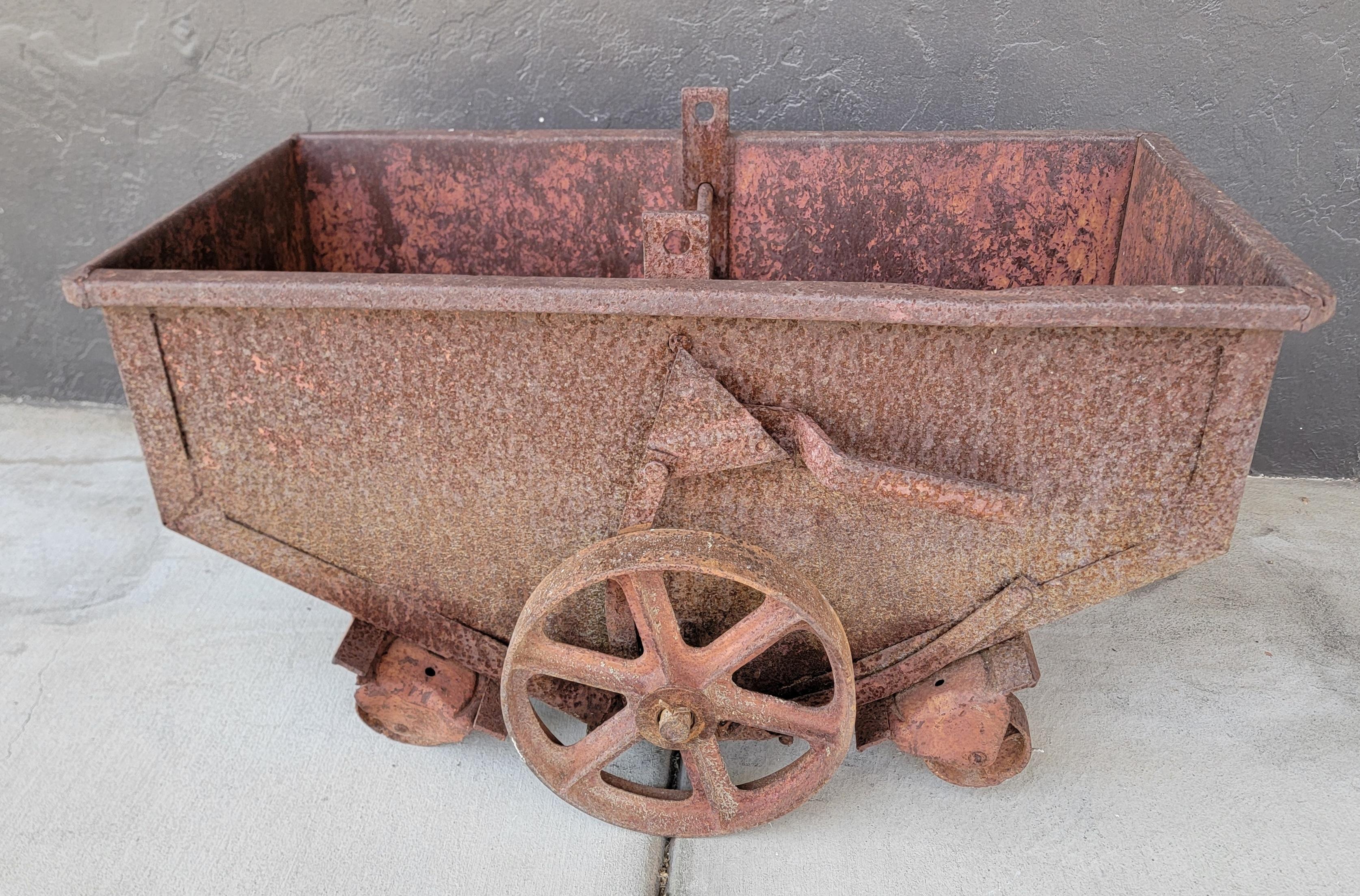 Heavy gauge steel industrial cart / dolly with large cast iron spoke wheels. Four smaller castor wheels. Probably used in a factory to move material for production. Designed to hold a substantial amount of weight. Traces of original iron oxide