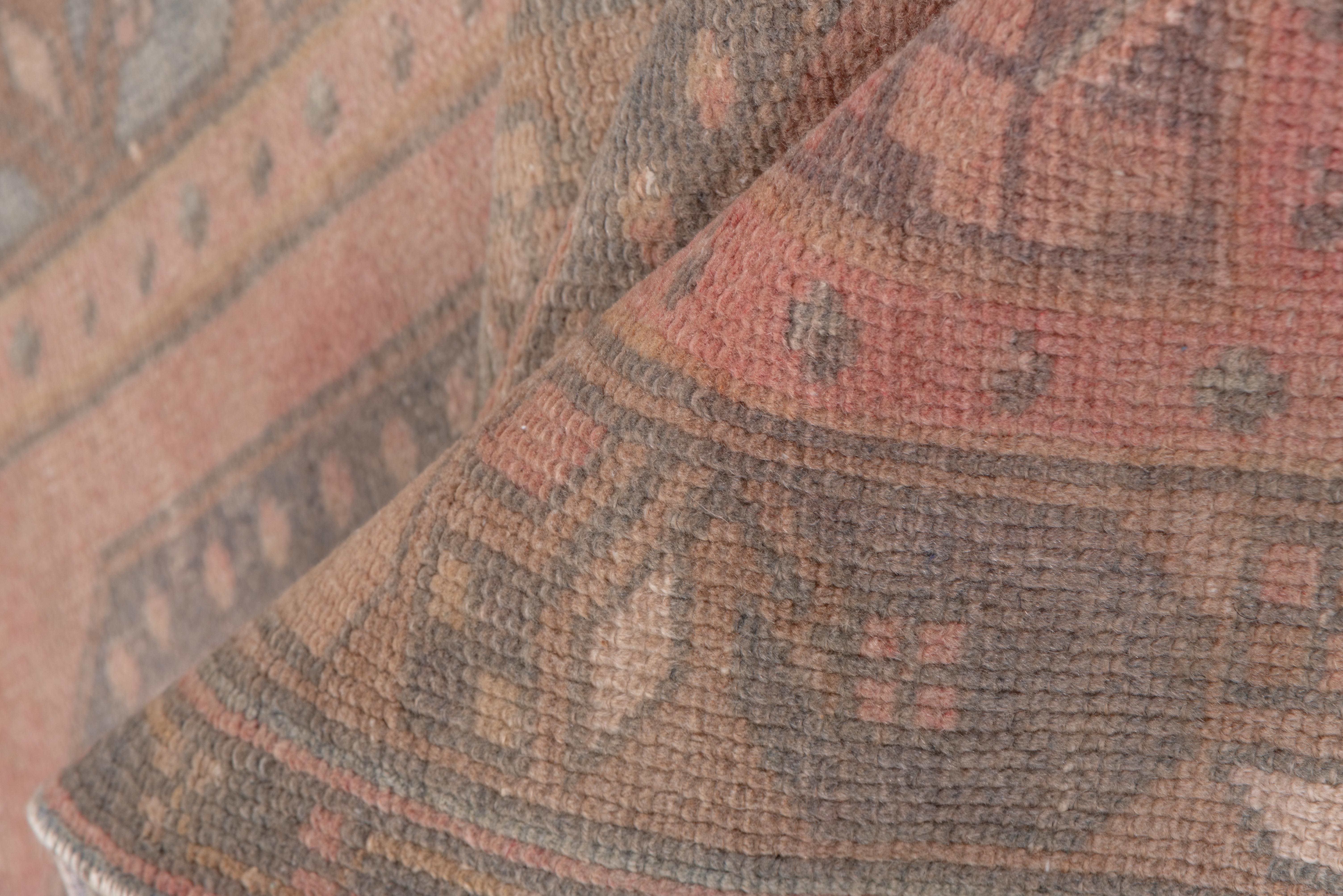 Dieser Vintage-Teppich aus Oushak zeichnet sich durch eine wunderschön abgenutzte Farbpalette aus sanften Blush-, Taupe- und gedämpften Grautönen aus. Zwei geometrische Medaillons bilden den Mittelpunkt des Teppichs, flankiert von zarten floralen