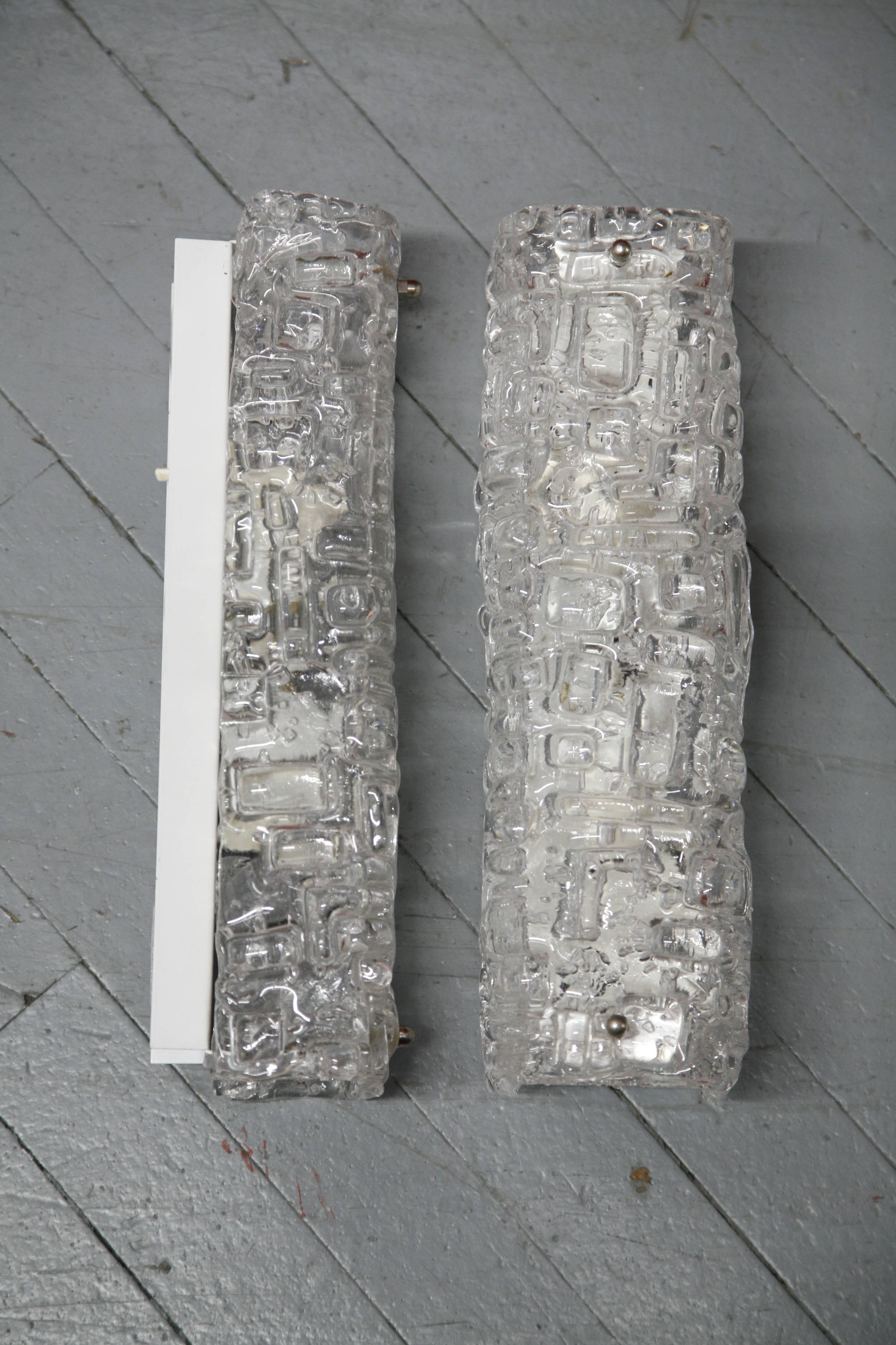 Paire d'appliques suédoises simples et élégantes de Fagerhult, une structure en métal avec un abat-jour en verre clair texturé, des finitions en nickel et des bases blanches.

Rewired pour les États-Unis.