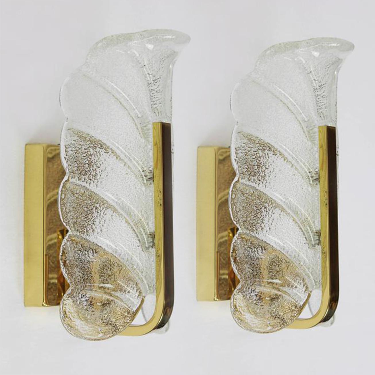 Un magnifique ensemble de deux lustres suspendus à 8 bras avec 8 abat-jour en verre et cadre en laiton et 2 appliques murales avec un abat-jour en verre et cadre en laiton. Les luminaires sont produits dans les années 1960 par la firme emblématique