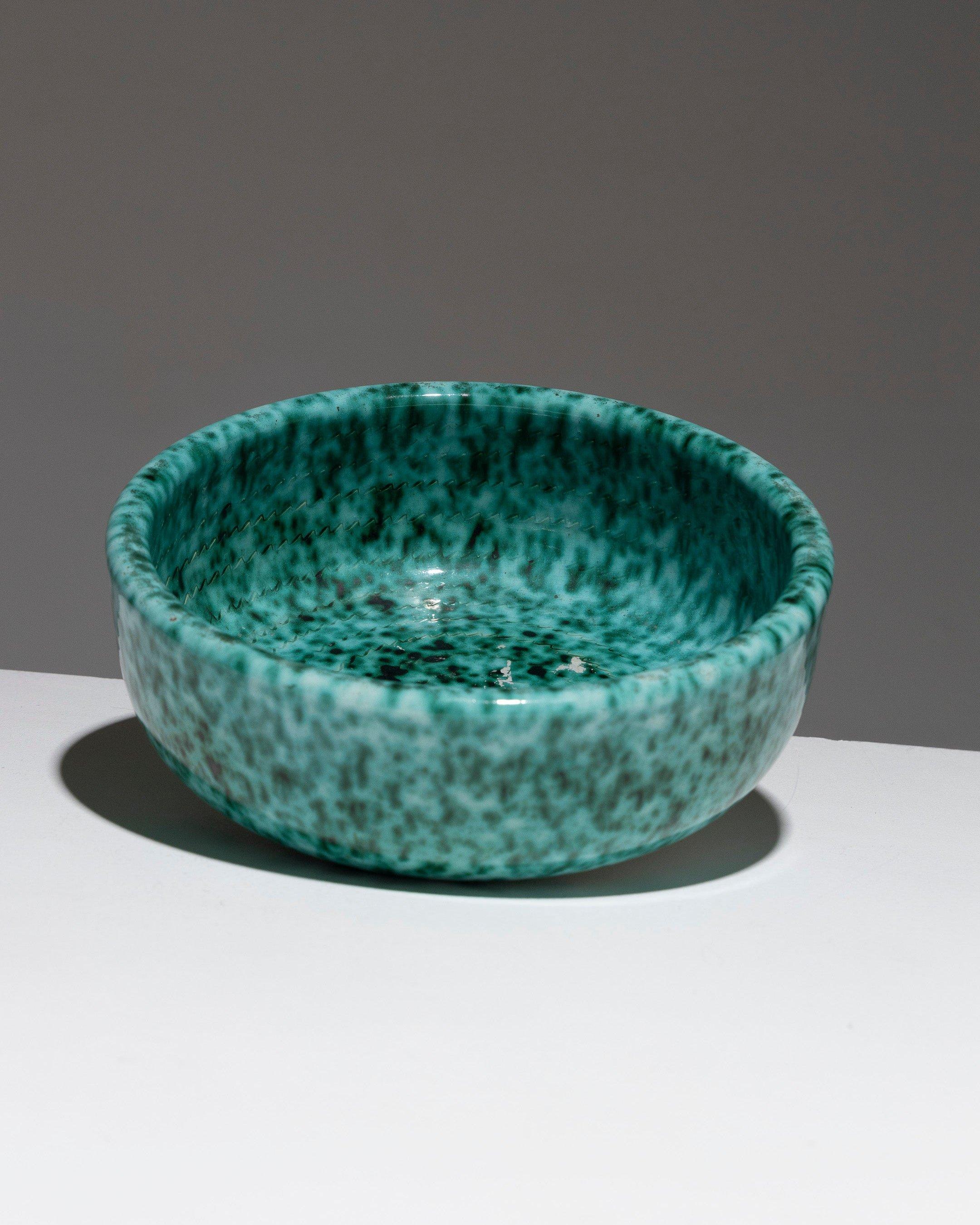 Cuenco de loza con borde alto de Fernand Elchinger, años 50. El vidriado verde cobrizo oscuro está moteado de blanco, y en el interior hay grabado un motivo de lazo. Marca impresa bajo la base: 'Céramique d'Art / Elchinger Fils / ....' Muy buen