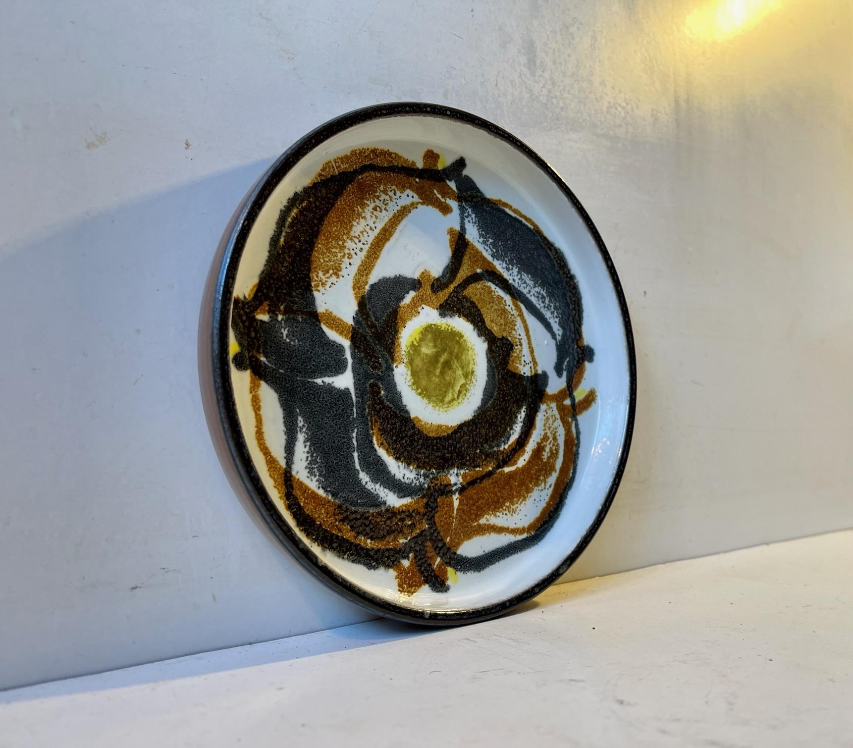 A fajance bowl with abstract - modernistic glazed motif in contrasting glazes. Both designed by the danish ceramist Ellen Malmer (EM) and manufactured by Royal Copenhagen during the 1970s. Its fully signed, numbered and marked to the base.