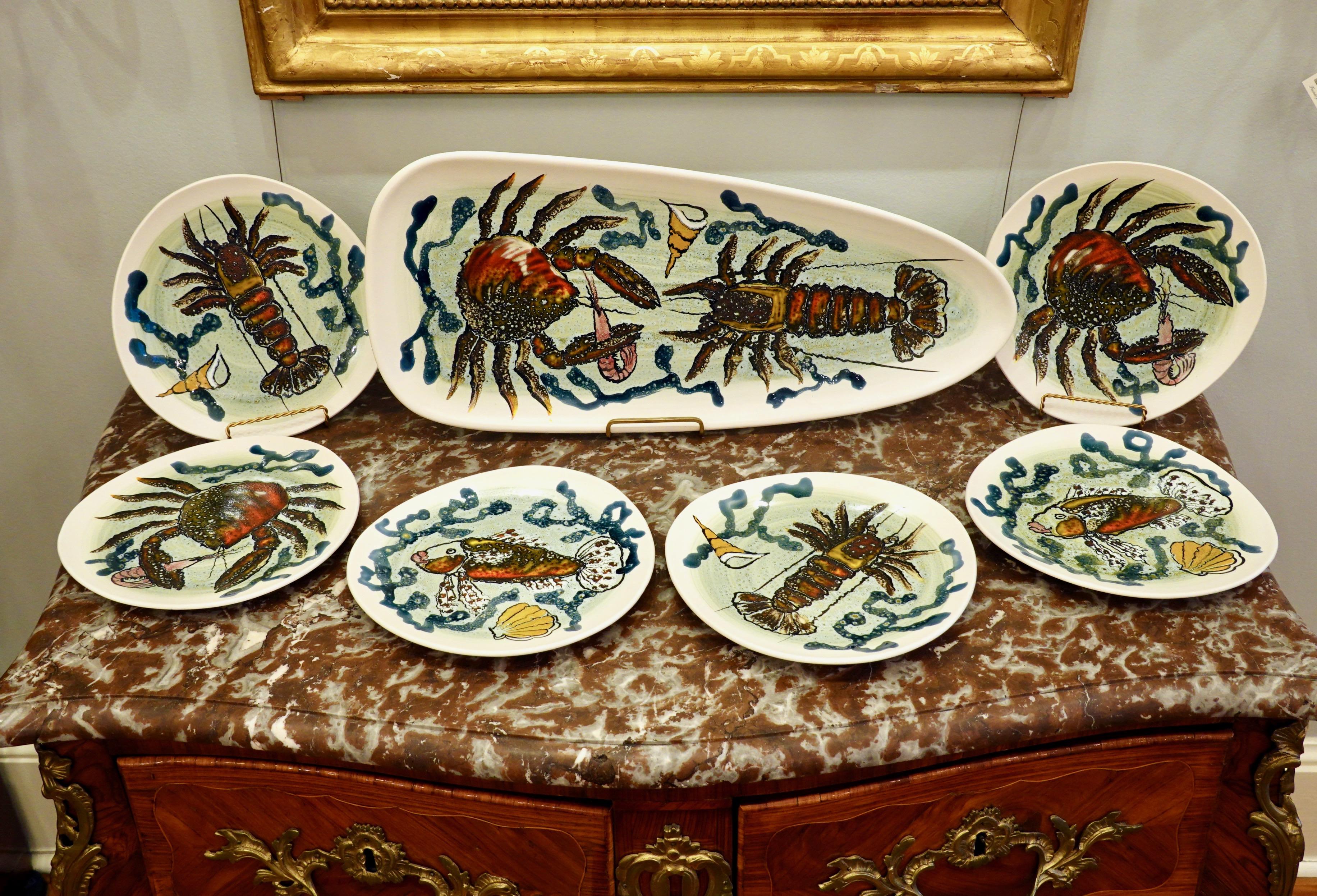 14 piece highly-decorative French hand painted faience fish service, featuring lobsters, crabs, fish and other sea life. The service consists of a platter (about 24
