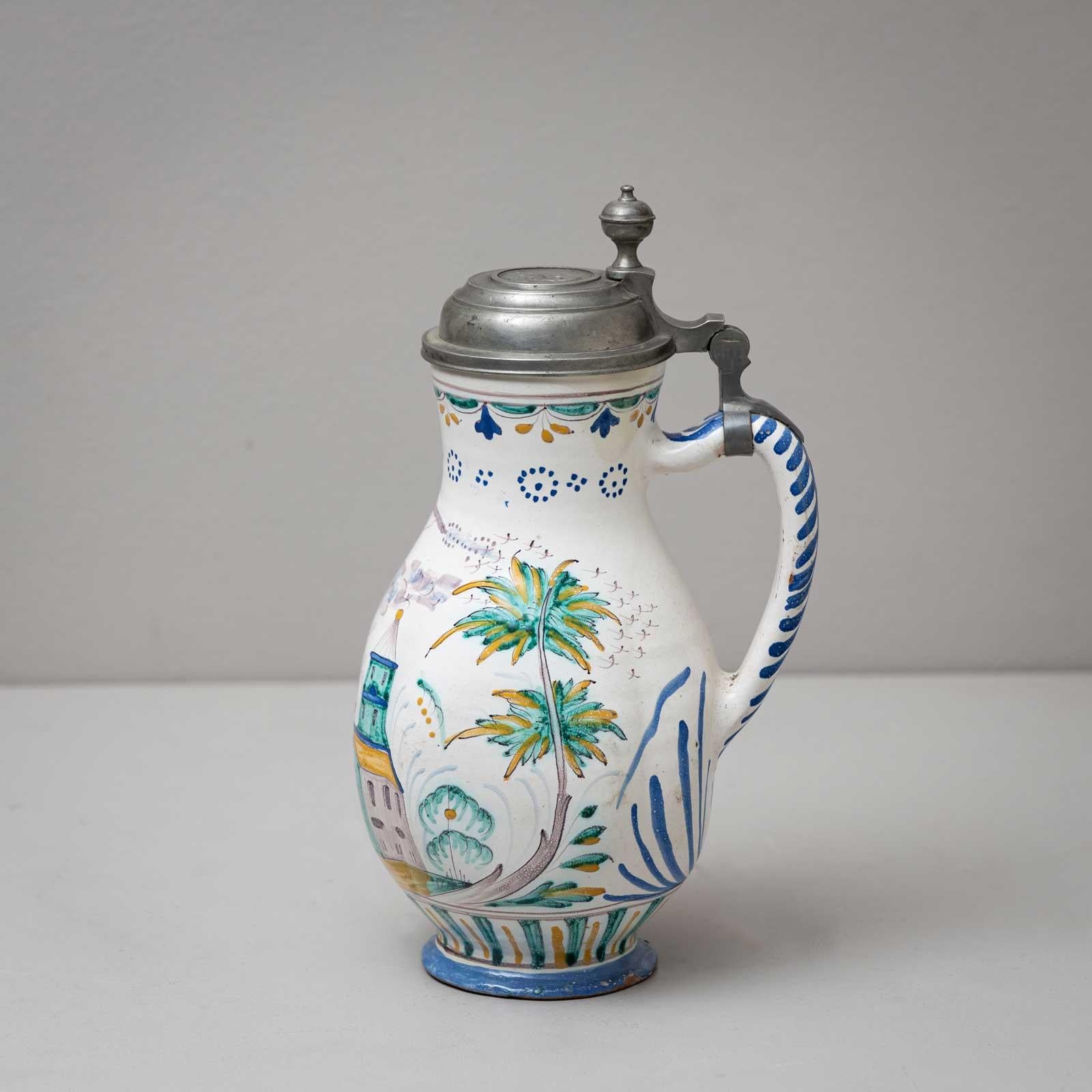Pear-shaped faience jug with pewter mounting and coin in the lid, showing Pontifex Martinus II in profile to the left. The inscription reads ‘S. Martinus II Pont. Max.’ The wall is painted in colour and shows a marksman with a rifle against a city