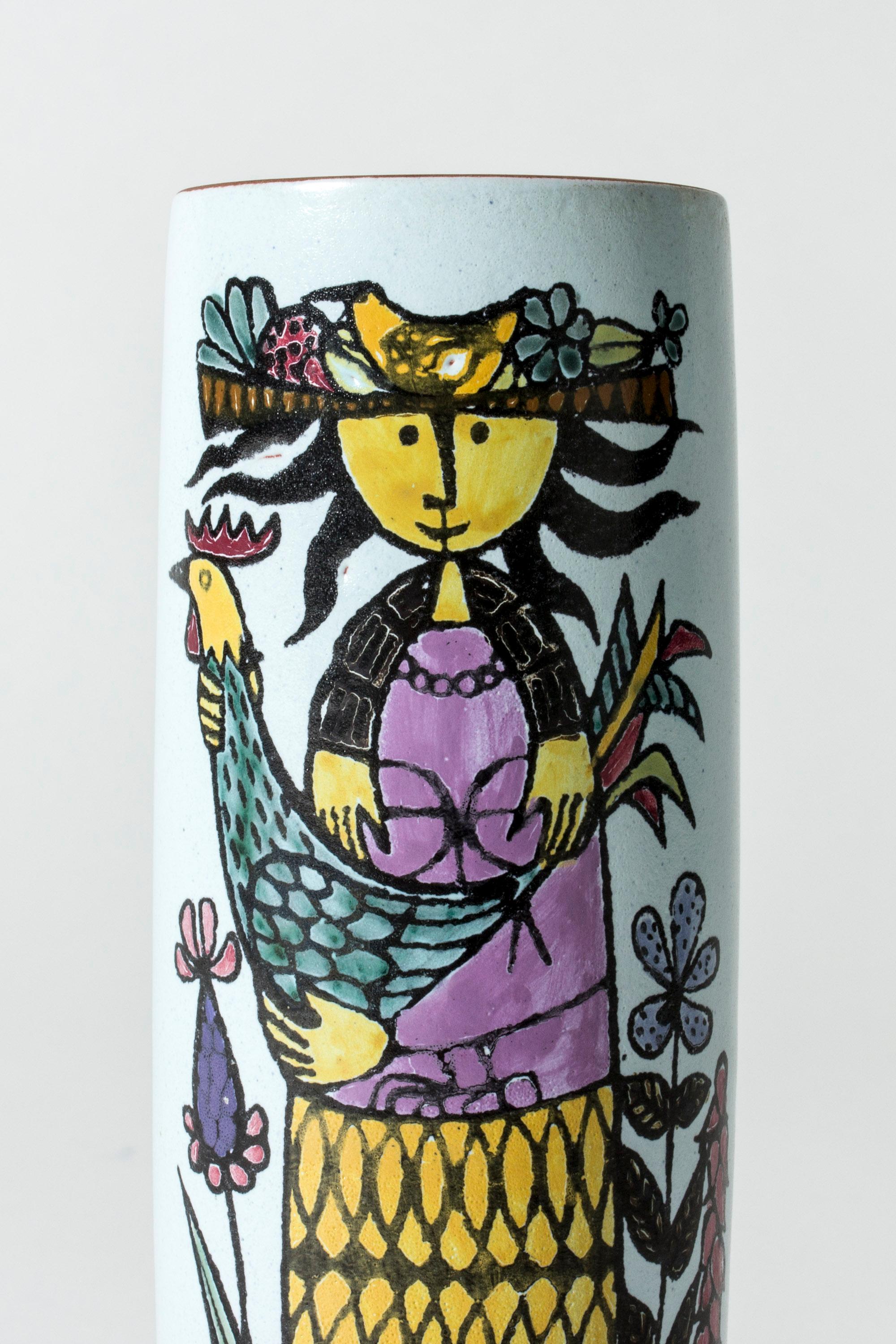 Faience “Karneval” vase by Stig Lindberg, in a clean cylinder shape. Beautiful, playful motif of a woman with a rooster in her arms on one side, and a bird on the other. The rim is unglazed, giving an organic touch to the smooth design.

The