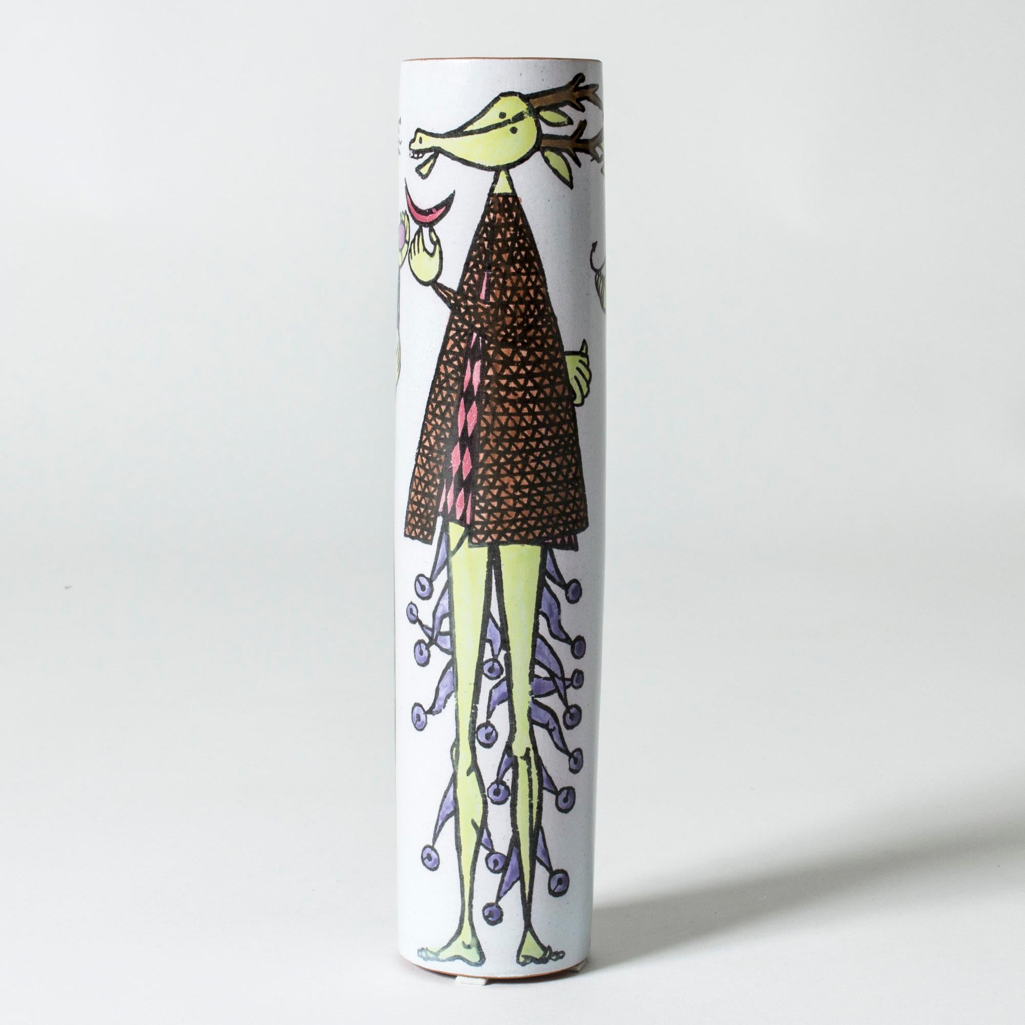 Faience “Karneval” vase by Stig Lindberg, in a long cylinder shape. Beautiful, playful motif of a three people in imaginative clothes. The rim is unglazed, giving an organic touch to the smooth design.

The “Karneval” series was produced from 1958