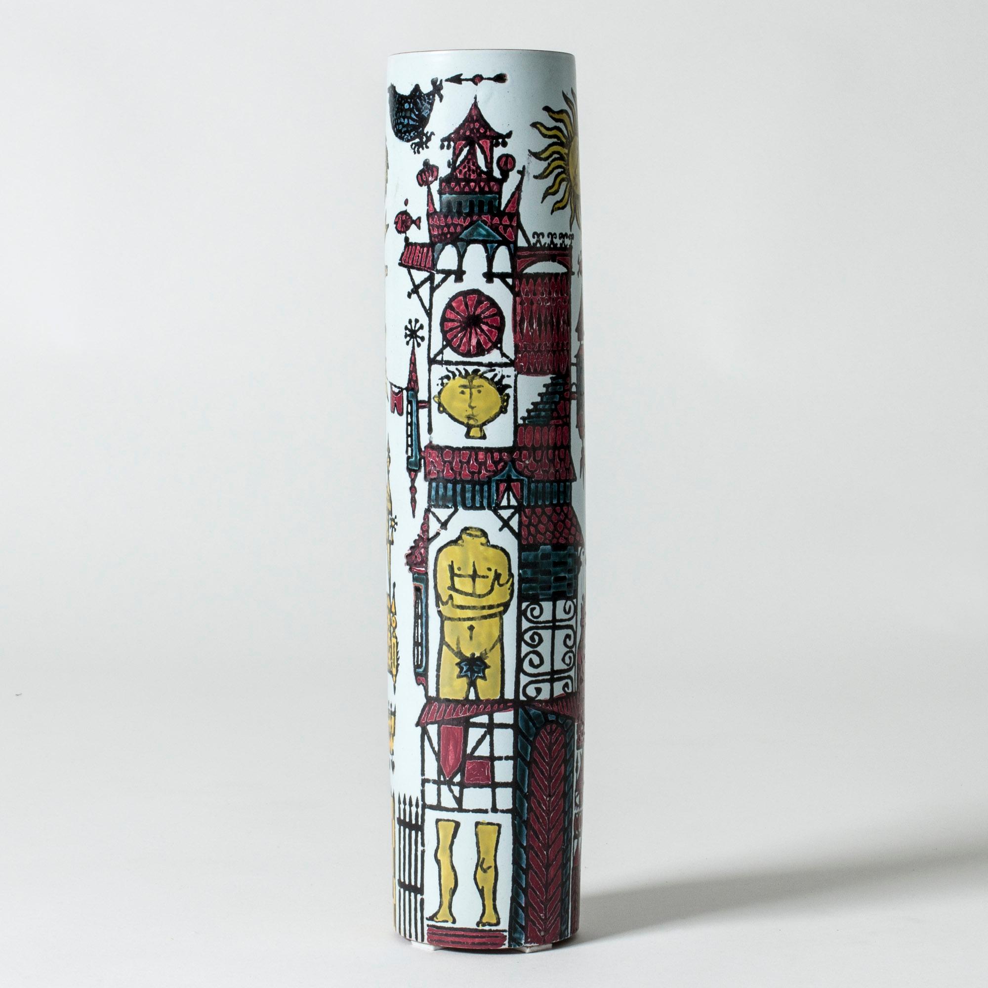Faience “Karneval” vase by Stig Lindberg, in a long cylinder shape. Beautiful, playful motif of a fantasy town with graphic houses and people. The rim is unglazed, giving an organic touch to the smooth design.

The “Karneval” series was produced