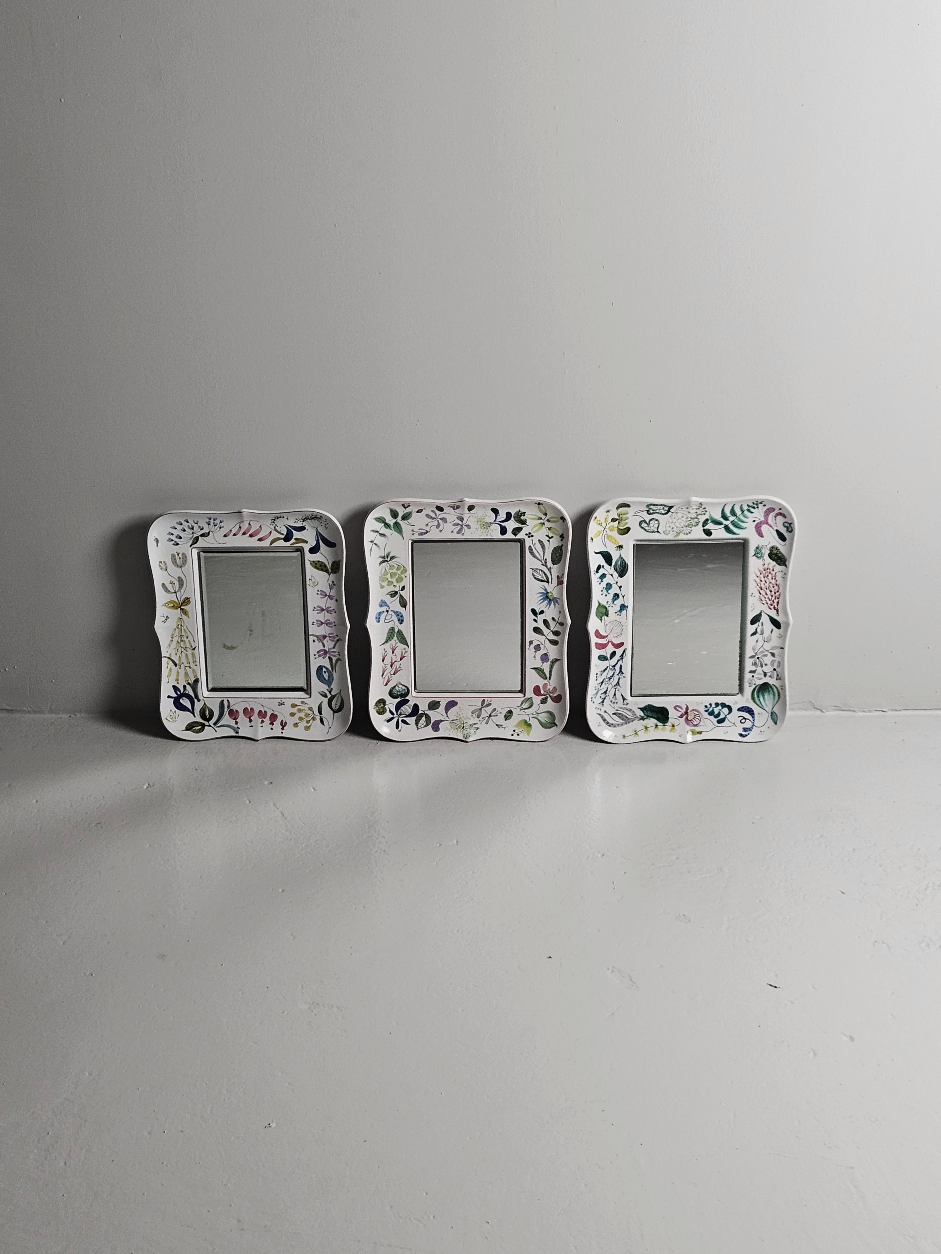 Lovely faience wall mirrors designed by Stig Lindberg. 

Everyone of the mirrors has a different floral painting on them. 

It is possible to hang the mirror horizontally as well as vertically