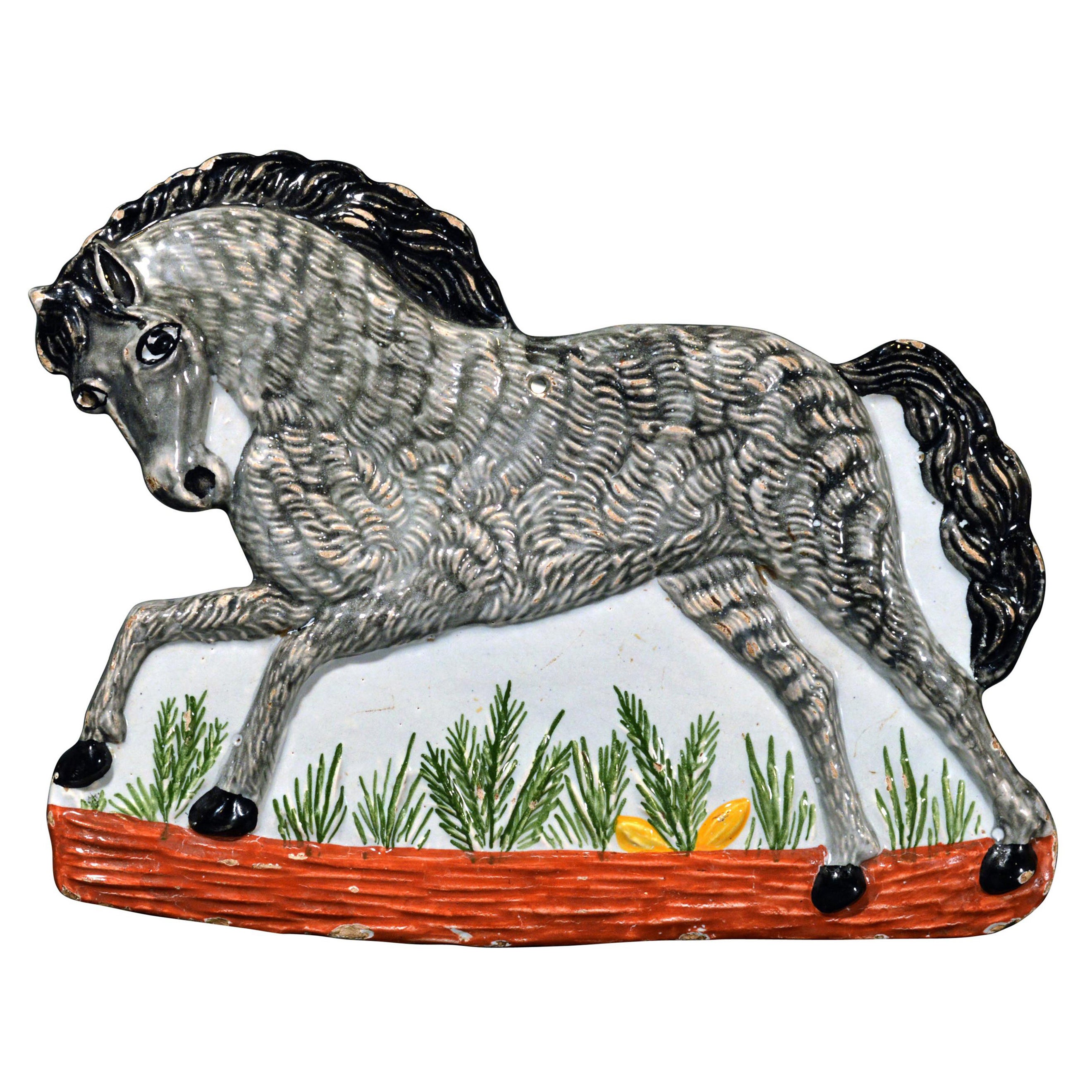 Plaque de faïence continentale en forme de cheval,
vers 1840,
Probablement Rorstrand.

La plaque est décorée de façon amusante d'un cheval gris galopant avec une longue queue et une crinière noires moulées en trois dimensions. Sous ses pattes se