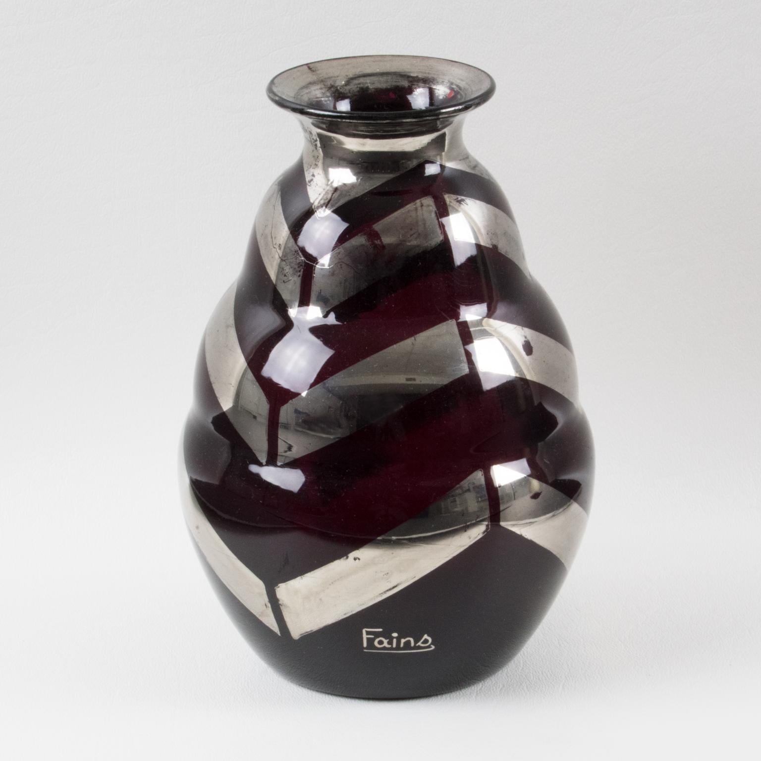 This is a stylish Art Deco black opaline glass vase by Fains, France, in the 1930s. The vase is decorated with a silver deposit in a geometric zig-zag pattern. The vase is marked 