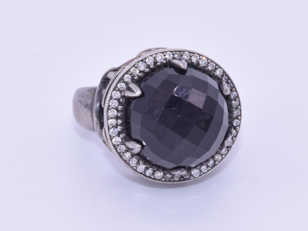 A faceted domed onyx is set in a surround of round diamonds totaling approximately 0.41 carat mounted in blackened silver in an architectural inspired ring by designer Faith Ann Kiely. Ring size 6.75.