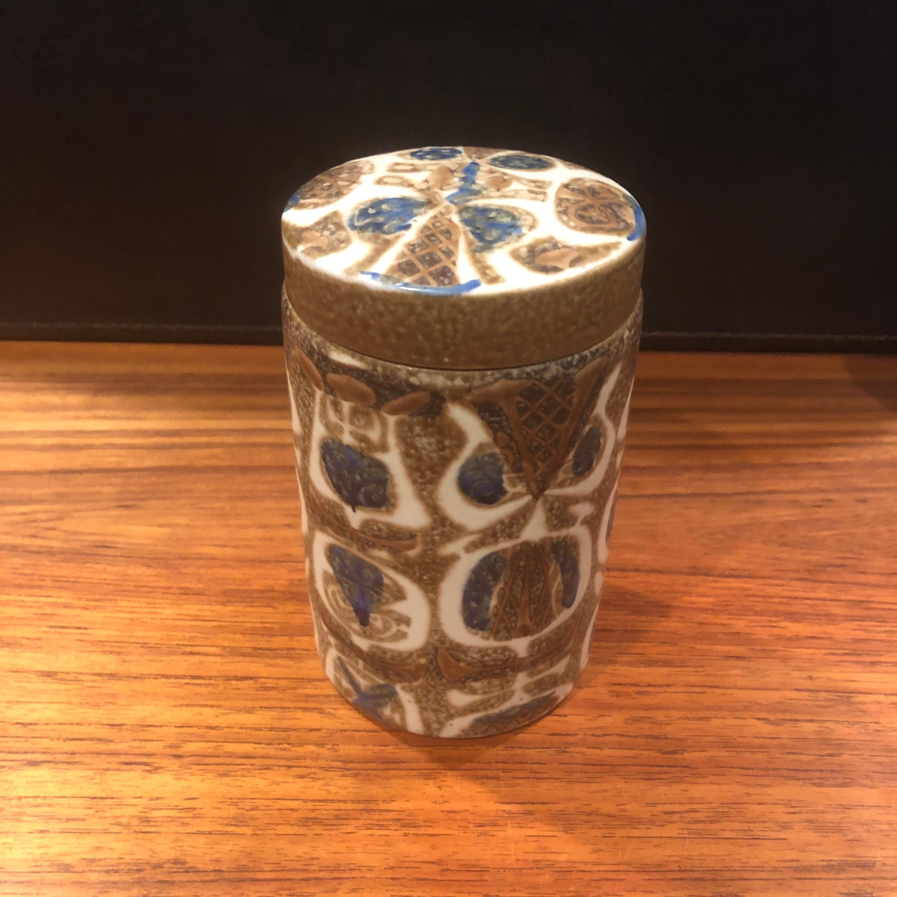 Pot à couvercle / humidor en céramique Fajance de la ligne Baca de Nils Thorsson pour Royal Copenhagen, vers les années 1960. Cette jarre en grès émaillé brun, havane et bleu avec un motif géométrique abstrait en relief a été conçue par le célèbre