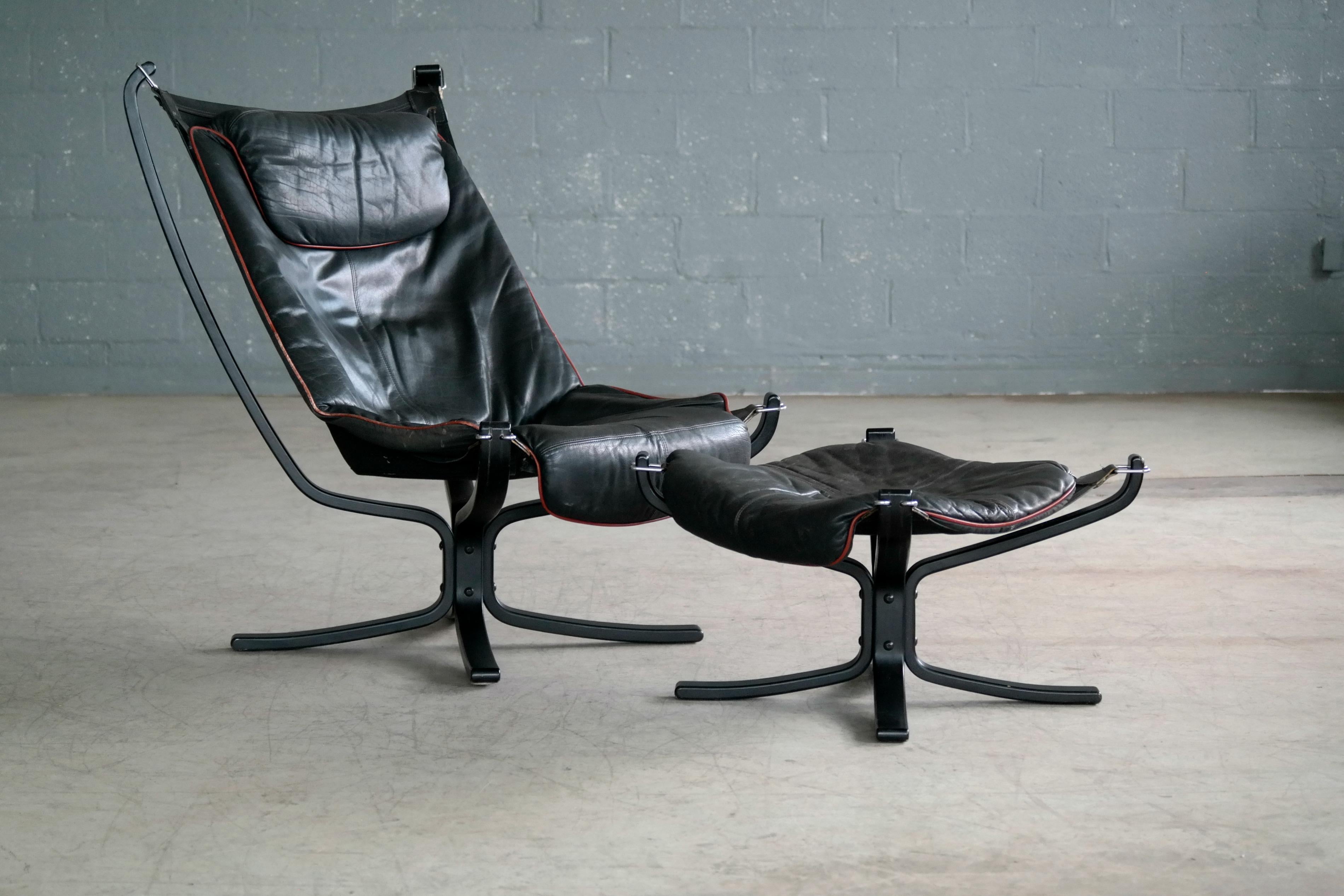 Beautiful and super elegant Falcon high back lounge chair plus a matching ottoman. Bases made from rosewood stained shaped beech ply with the supple leather cushion sitting in a cradle of black canvas mounted on leather straps with steel buckles.