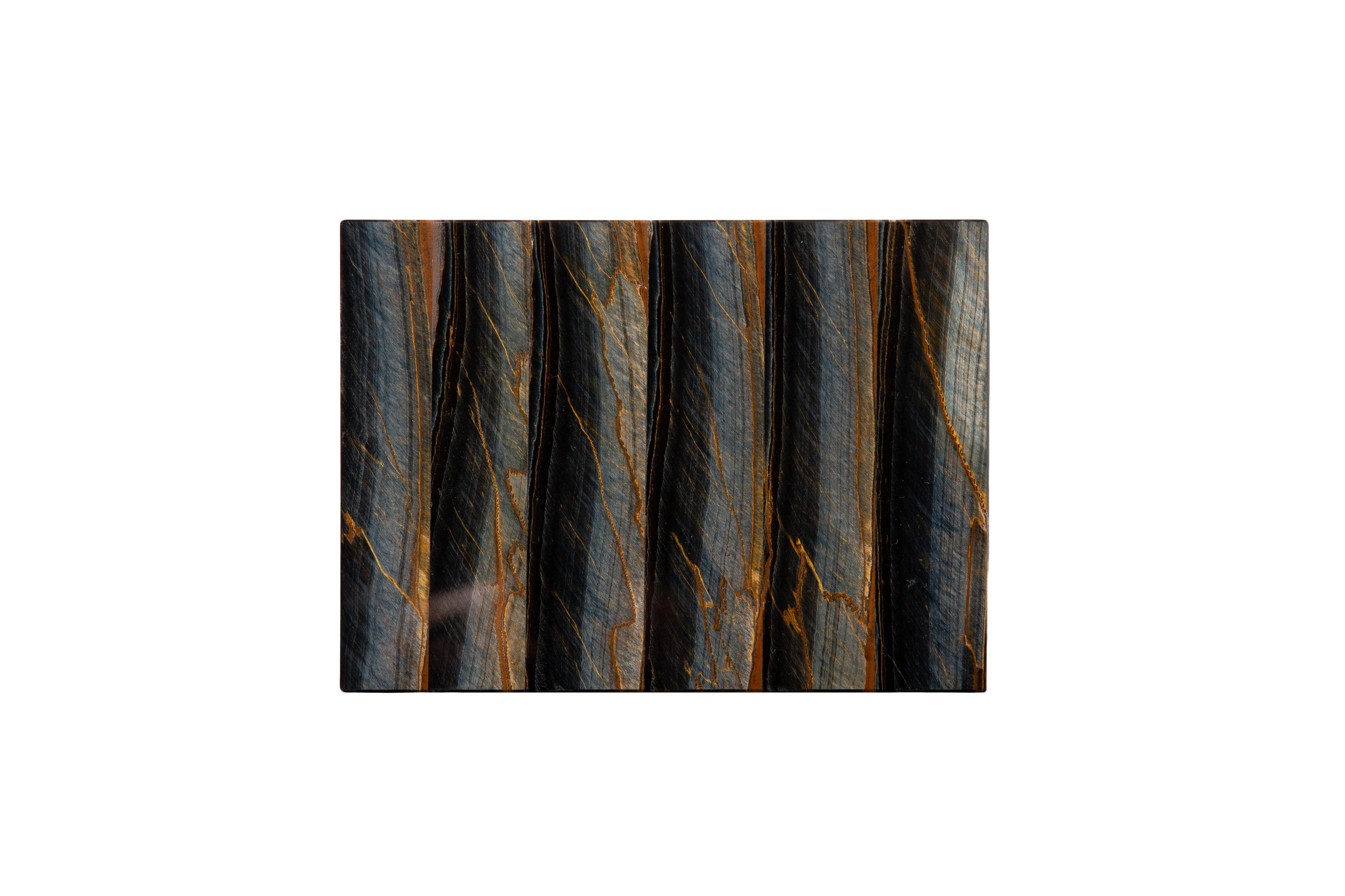 Dose aus Falkenauge-Halbedelstein mit Scharnierdeckel.
Das Falkenauge, auch bekannt als Blaues Tigerauge, ist für seine Chatoyanz berühmt und erinnert an das Auge eines Falken oder Habichts. Das Tigerauge wird eigentlich aus dem Falkenauge
