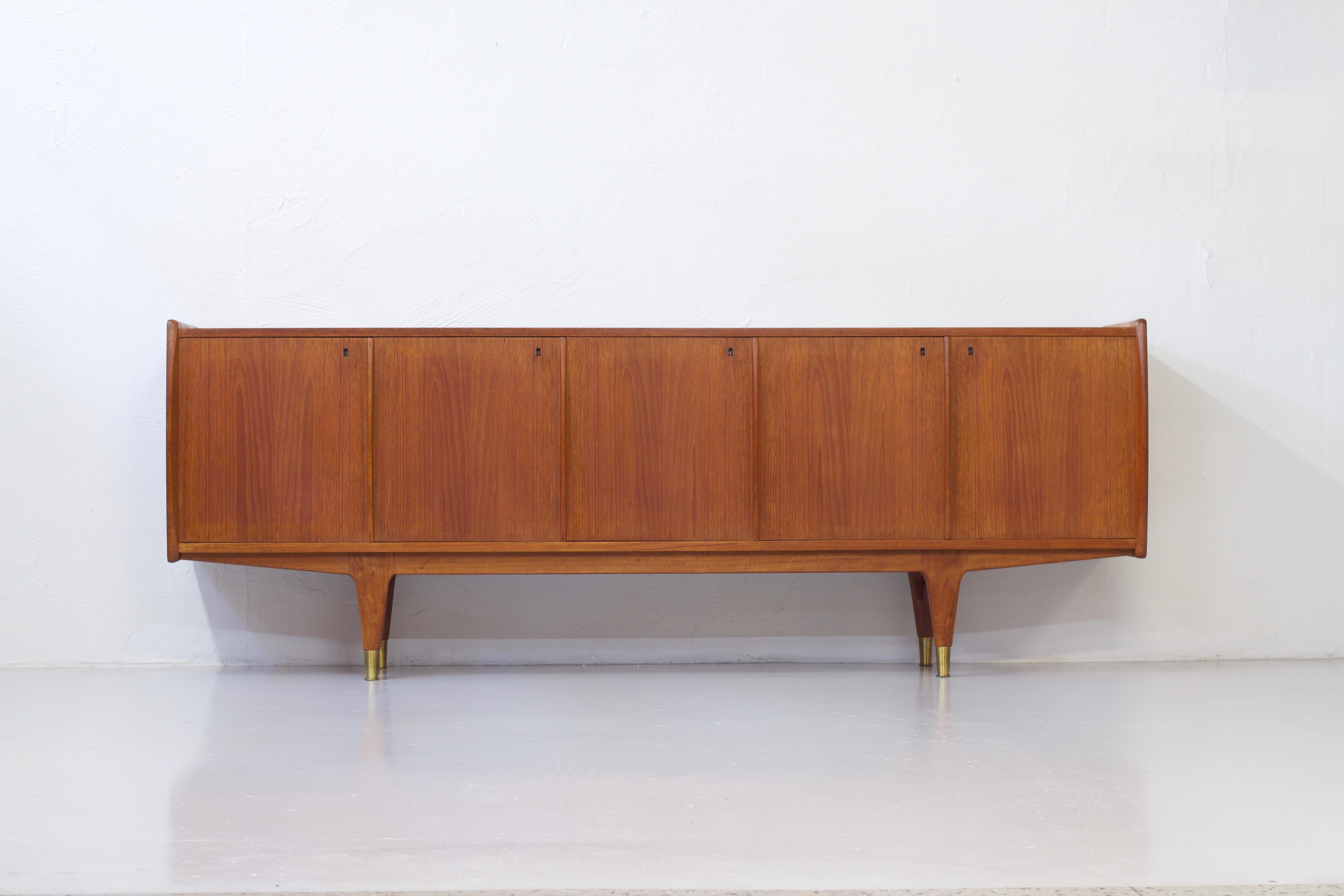 The Falk sideboard was designed by the dynamic Norwegian duo Rolf Rastas & Adolf Relling in the early 1960s. It’s made from teak and has a very nice detail in the brass feet. Front consists of five doors with shelving behind. Very good vintage