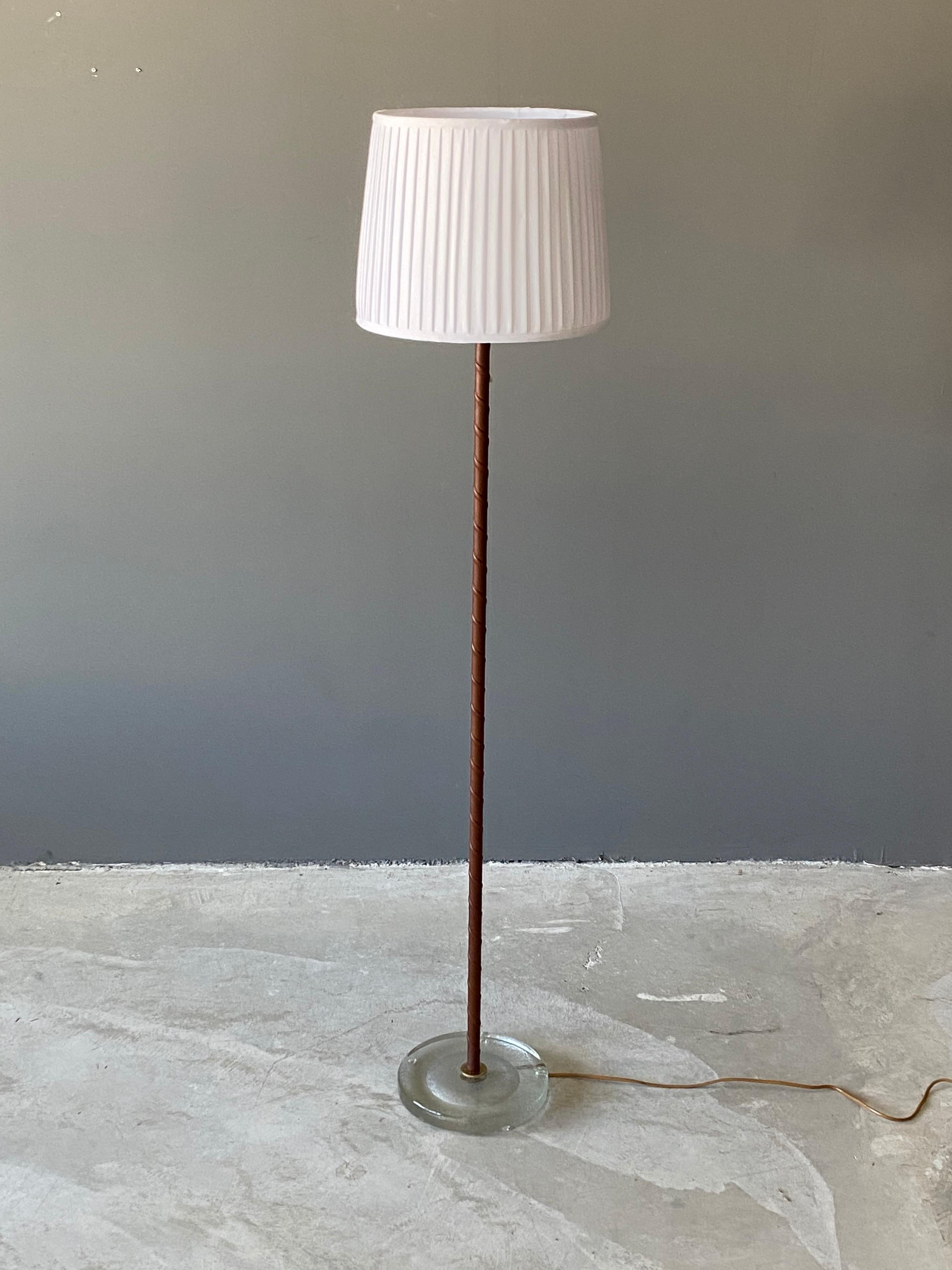 An all-original functionalist floor lamp. Produced by Falkenbergs Belysning. All original condition. Brass, wrapped leather rod, glass base. 

Lampshade is not included in purchase. Stated dimensions are without lampshade. Lampshade illustrated