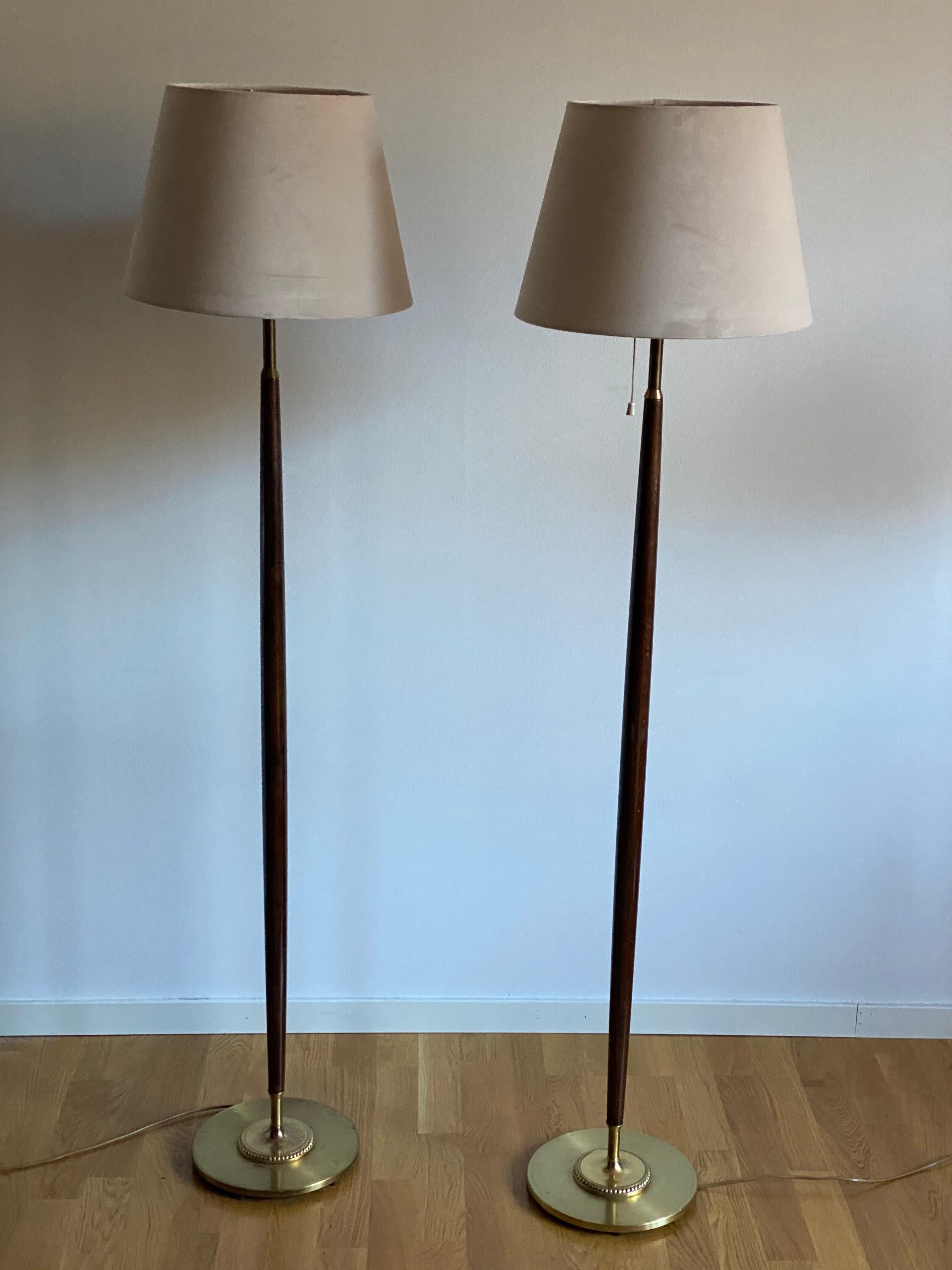 A pair of all-original functionalist floor lamps. Produced by Falkenbergs Belysning. All original condition. Stained walnut and brass.

Lampshades are attached for illustration and not included in the purchase. Dimensions stated are without