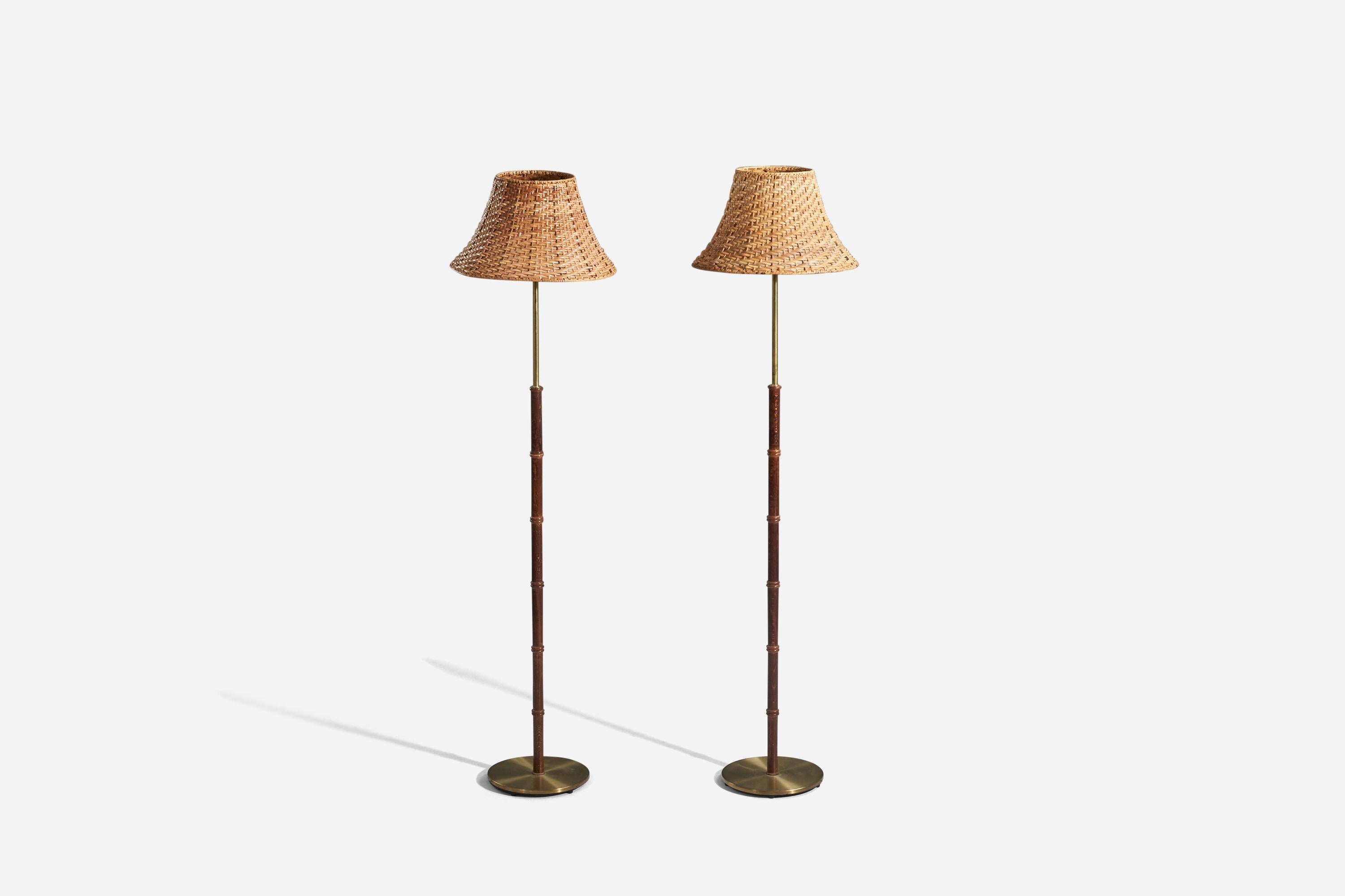 A pair of brass, stained walnut and rattan floor lamps designed and produced by Falkenbergs Belysning, Sweden, 1950s. 

Sold with Lampshade(s). 
Stated dimensions refer to the Floor Lamp with the Shade(s). 

Socket takes standard E-26 medium base