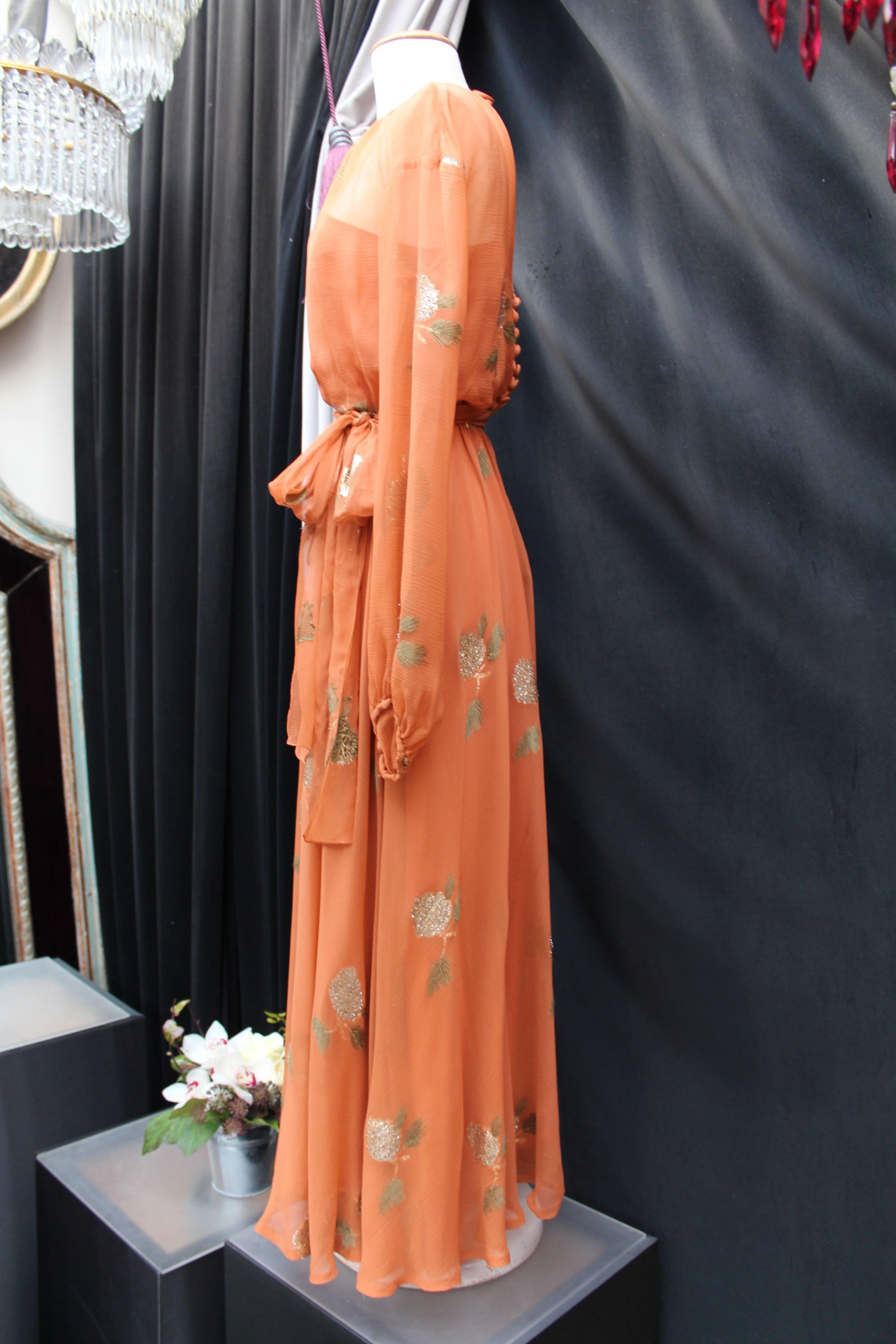 JEAN PATOU HAUTE COUTURE (Made in France) Long evening dress composed of rusty orange silk chiffon, decorated with green and gold lamé embroideries representing leaves. The long sheer chiffon sleeves are tightened at wrists. Back closure with a