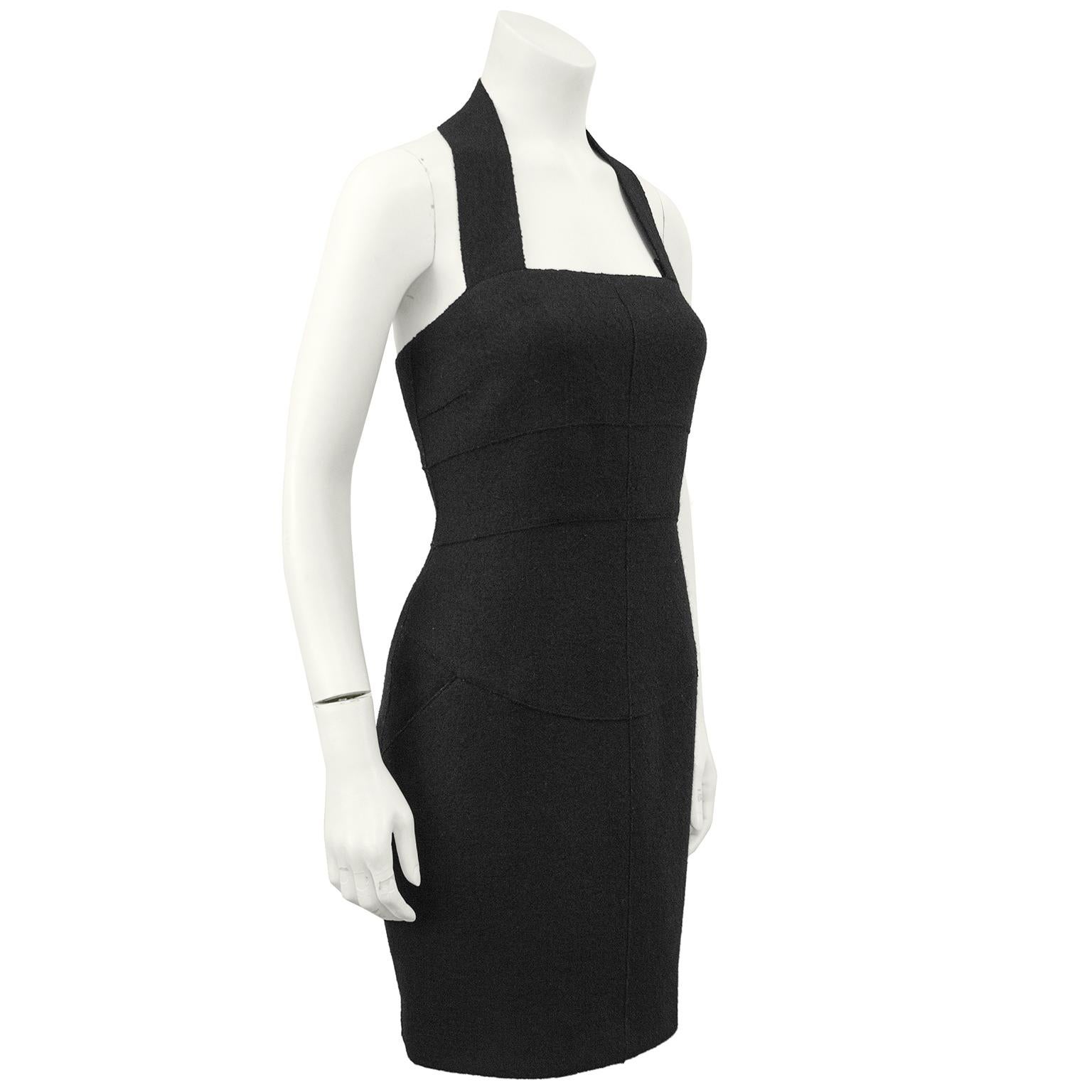 1999 Fall Chanel black wool halter dress with two hip front pockets and seaming down the front. The dress zips up the back and the thick halter strap fastens at the nape of the neck with a black CHANEL button. In excellent condition, fully lined in