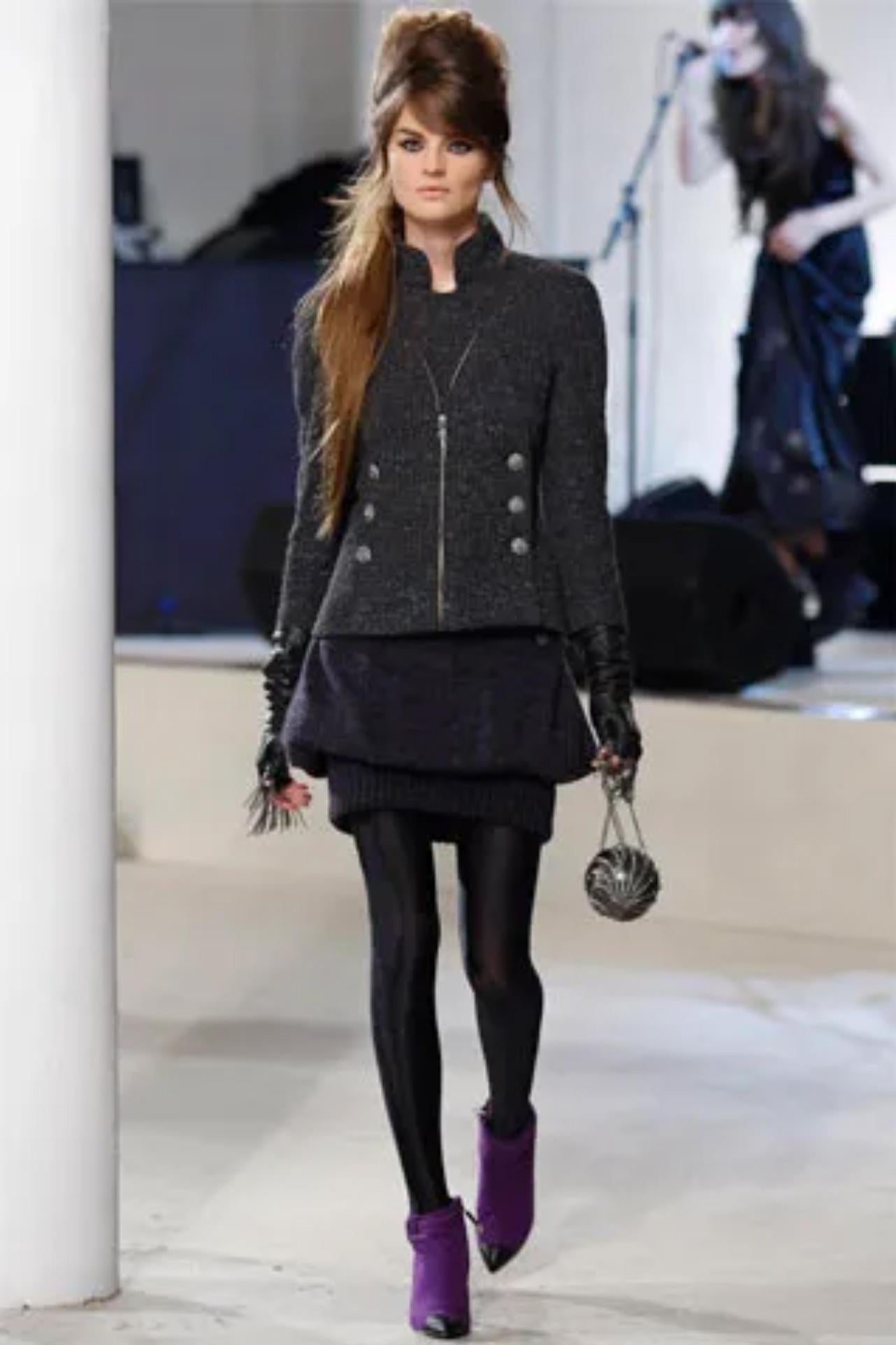 Chic Chanel gray boucle blazer from the Fall 2008 collection. The jacket is made of a steel gray boucle with speckles of lighter gray throughout. Double breasted buttons on the front that are adorned with large rhinestones and a faux moto style