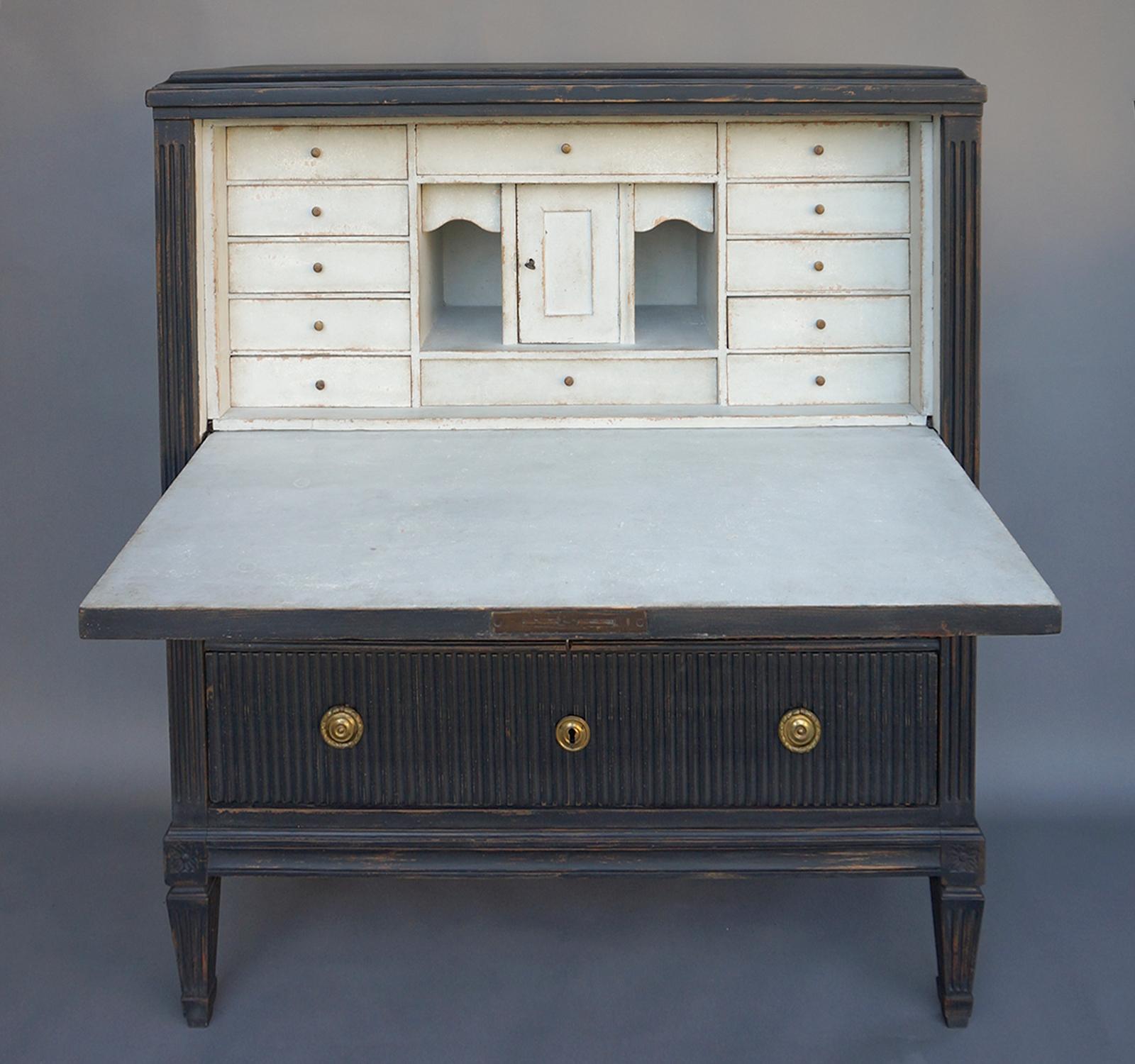 Swedish writing desk with a sophisticated design that reflects its Stockholm origin. The entire front is vertically reeded, with two full-width drawers under the fall-front. The interior is fitted with a central compartment and multiple drawers for