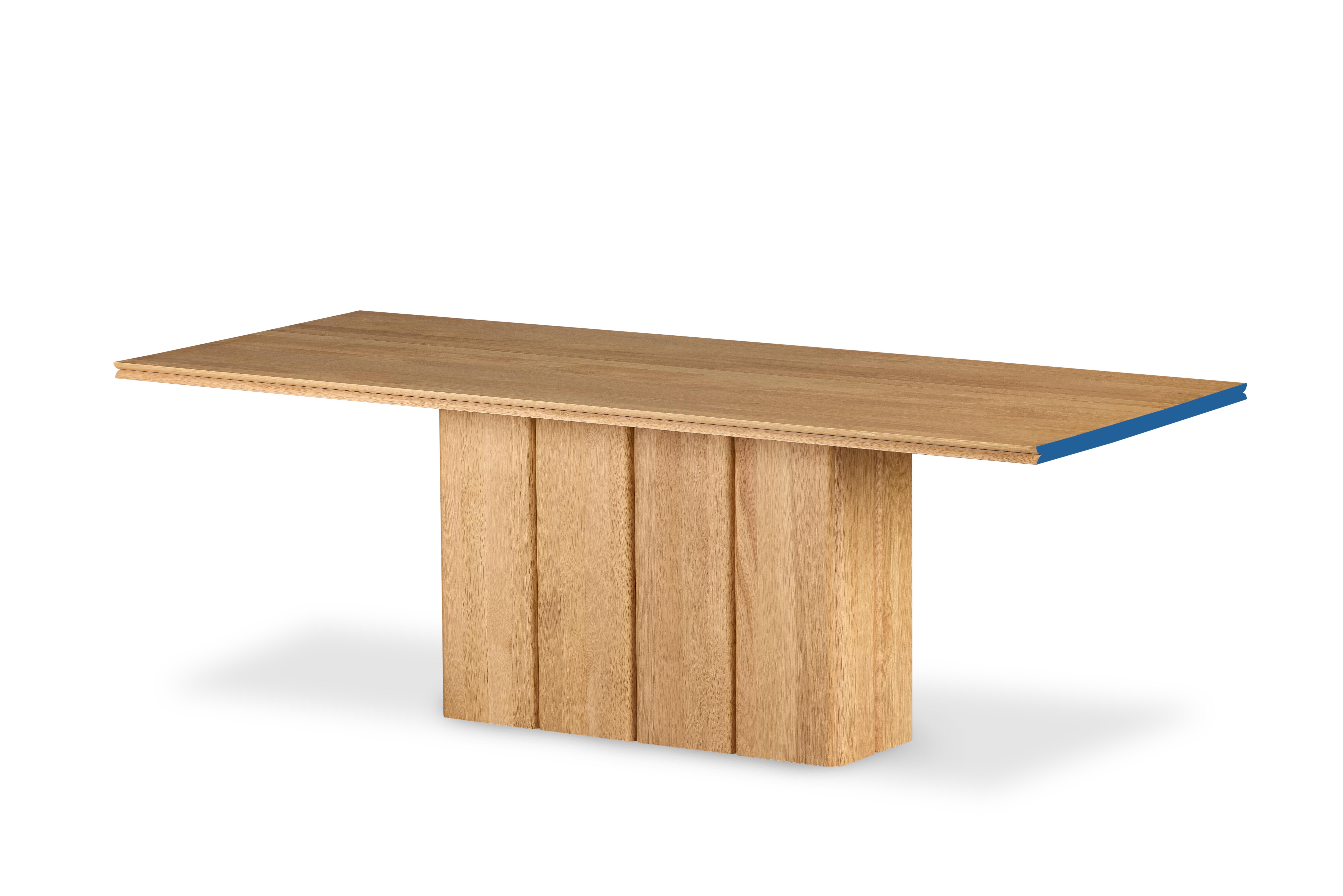 La table Fam Dining attire l'attention par ses lignes modernes et sa fonctionnalité. Le plateau en chêne massif offre durabilité et esthétique naturelle, tandis que le détail de la bande bleue ajoutée sur le bord confère à la table une touche