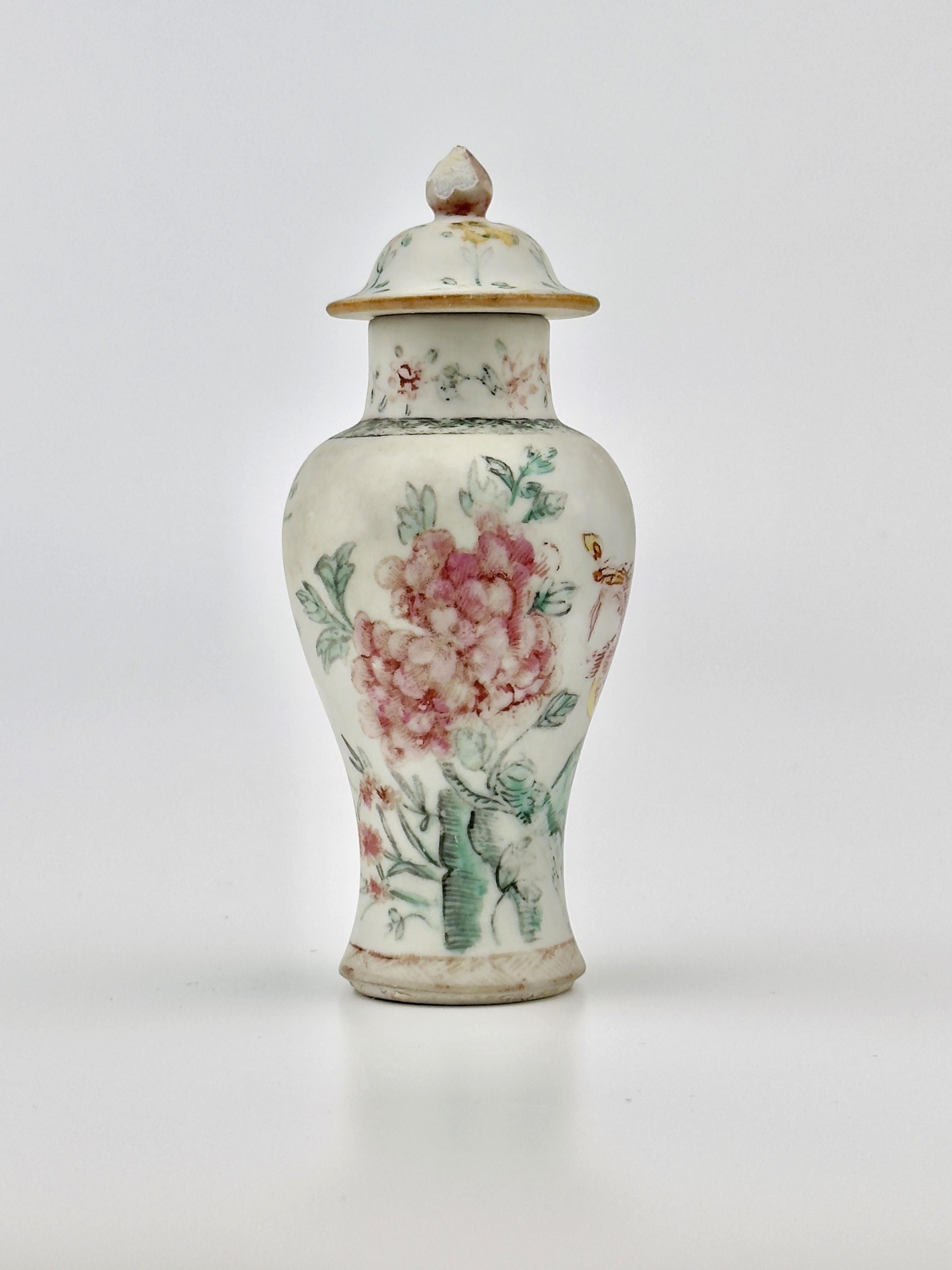 The famille rose enamels allowed for a greater expression of detail, seen here in the fine rendering of petals and feathers. The vase's form is elegant, with a tapered body and domed lid, crowned with a delicate finial, embodying the sophistication
