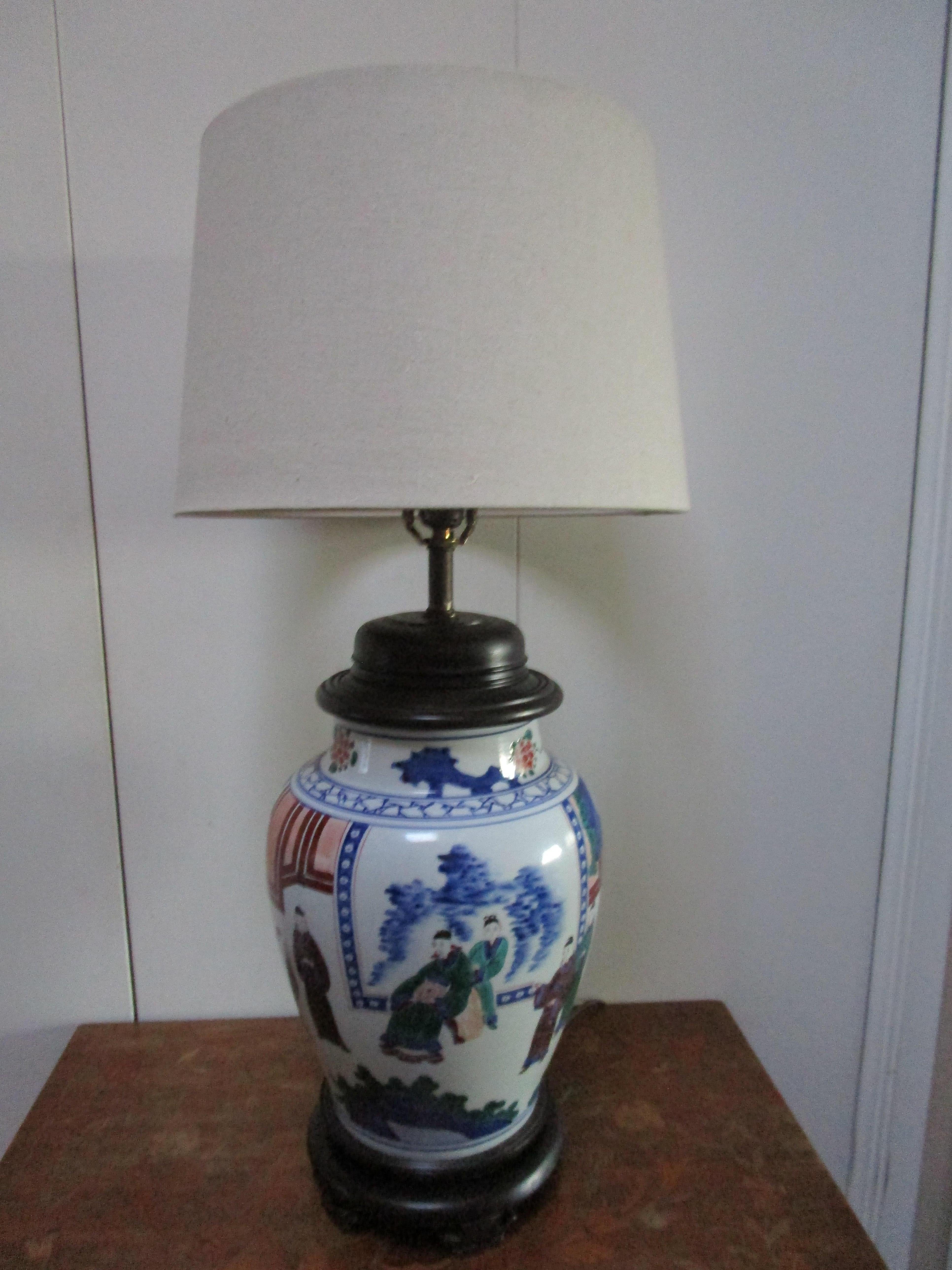 This mid century Chinese export lamp is an attention-getter for its scale and size. The vase with white ground enamel is in the form of a temple jar and colorful. Traditional Chinese export motif with scholars and landscape features.  It measures 35