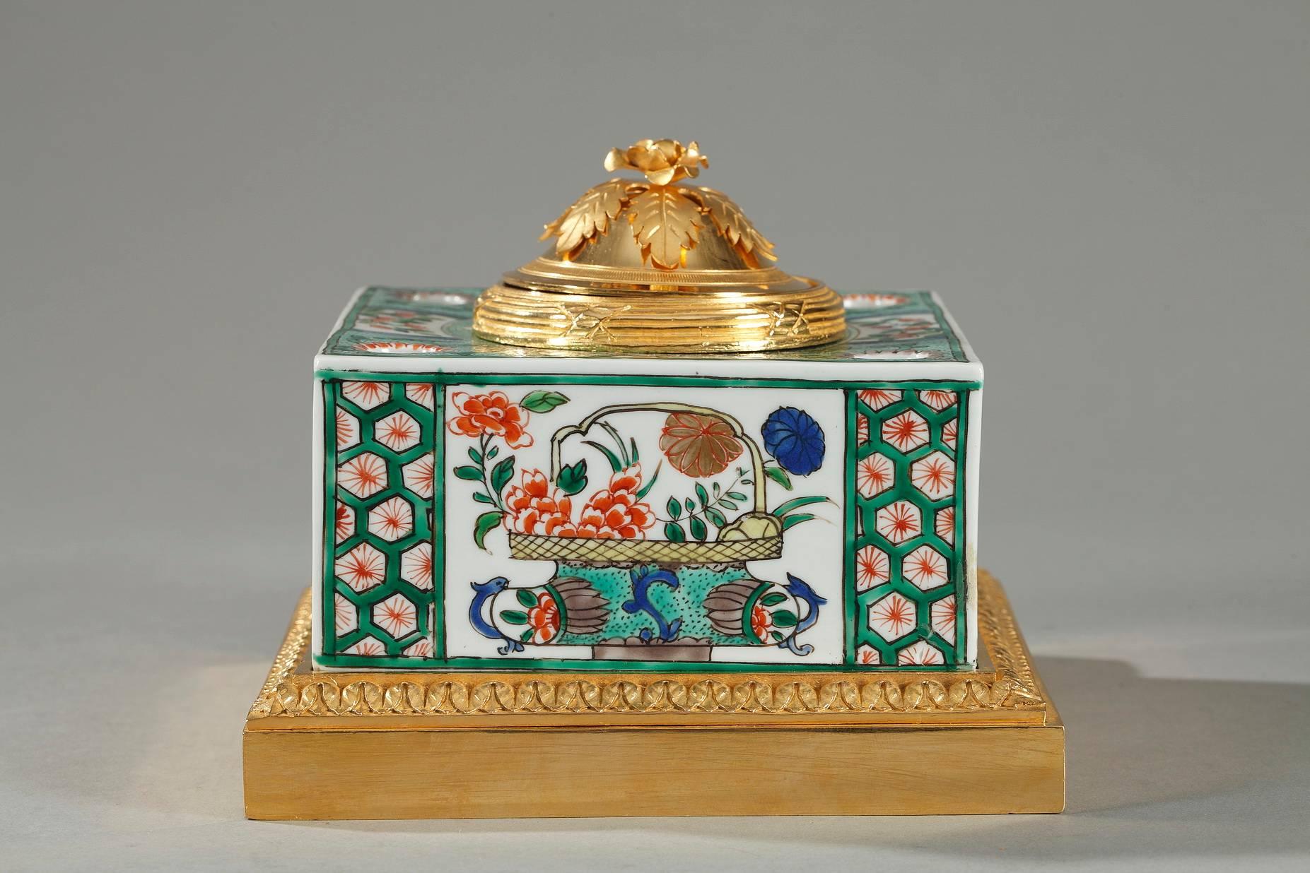 Small famille verte porcelain inkwell decorated with enameled flowerpots, foliage, and stylized rinceaux. The inkwell is set on a gilt bronze base that is decorated with palmette and bands embellished with interspaced latticework encircle the