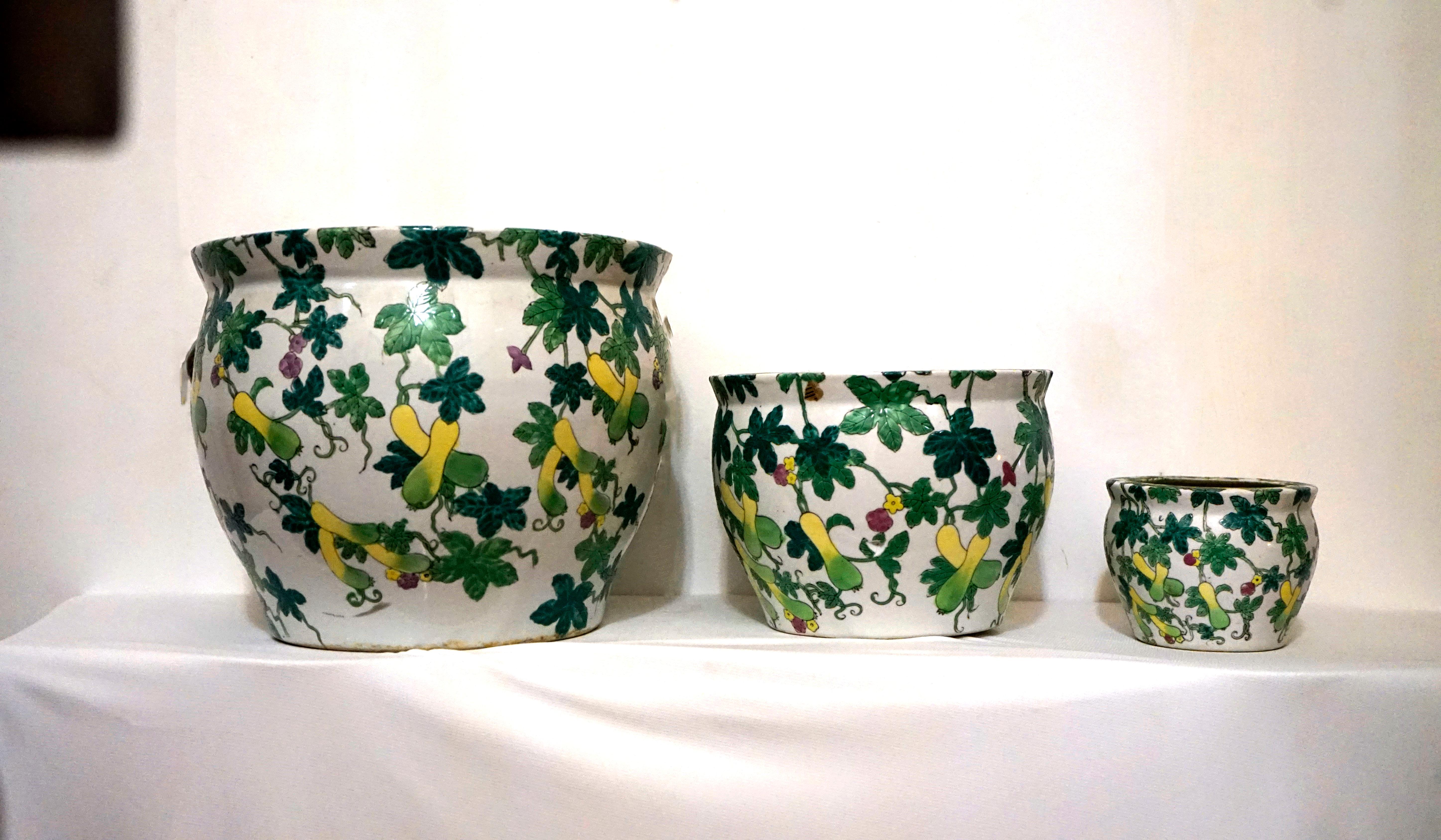 This graduated set of three Chinese export famille Verte pattern planters or fish bowls 
was made in China after 1919. 
The green white and yellow palette and ovoid form makes the pieces stand out on a background of green vegetables and leaves. Each
