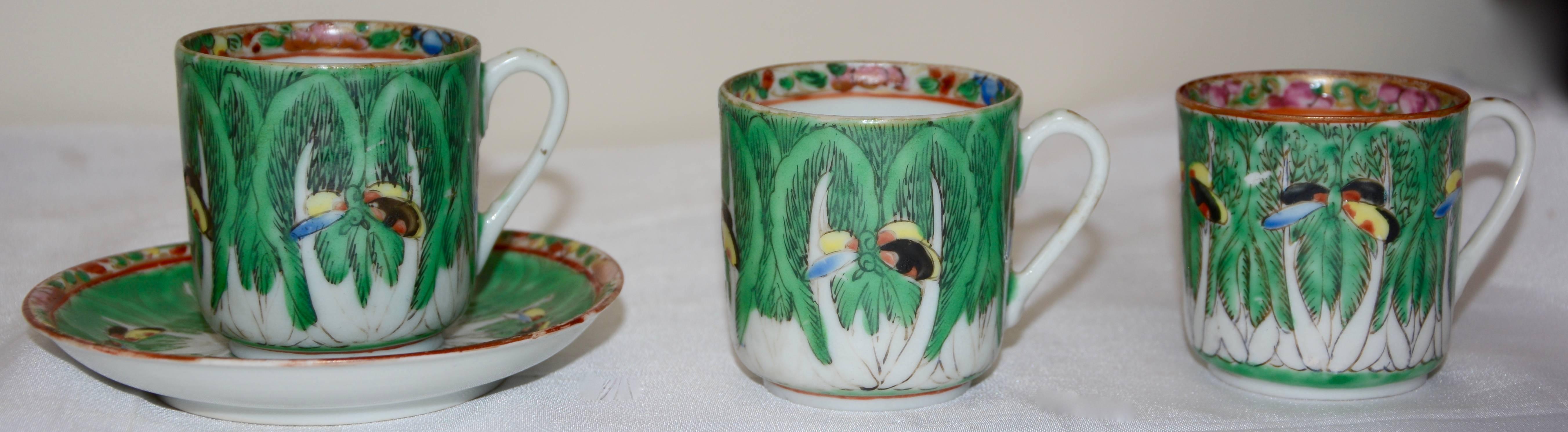 This set of porcelain consists of a dessert plate, saucer and three demitasse cups. They are hand painted with cabbage leaves and butterfly's floating about. The cups have a swirled border inside and the plates are edged the same. One cup is