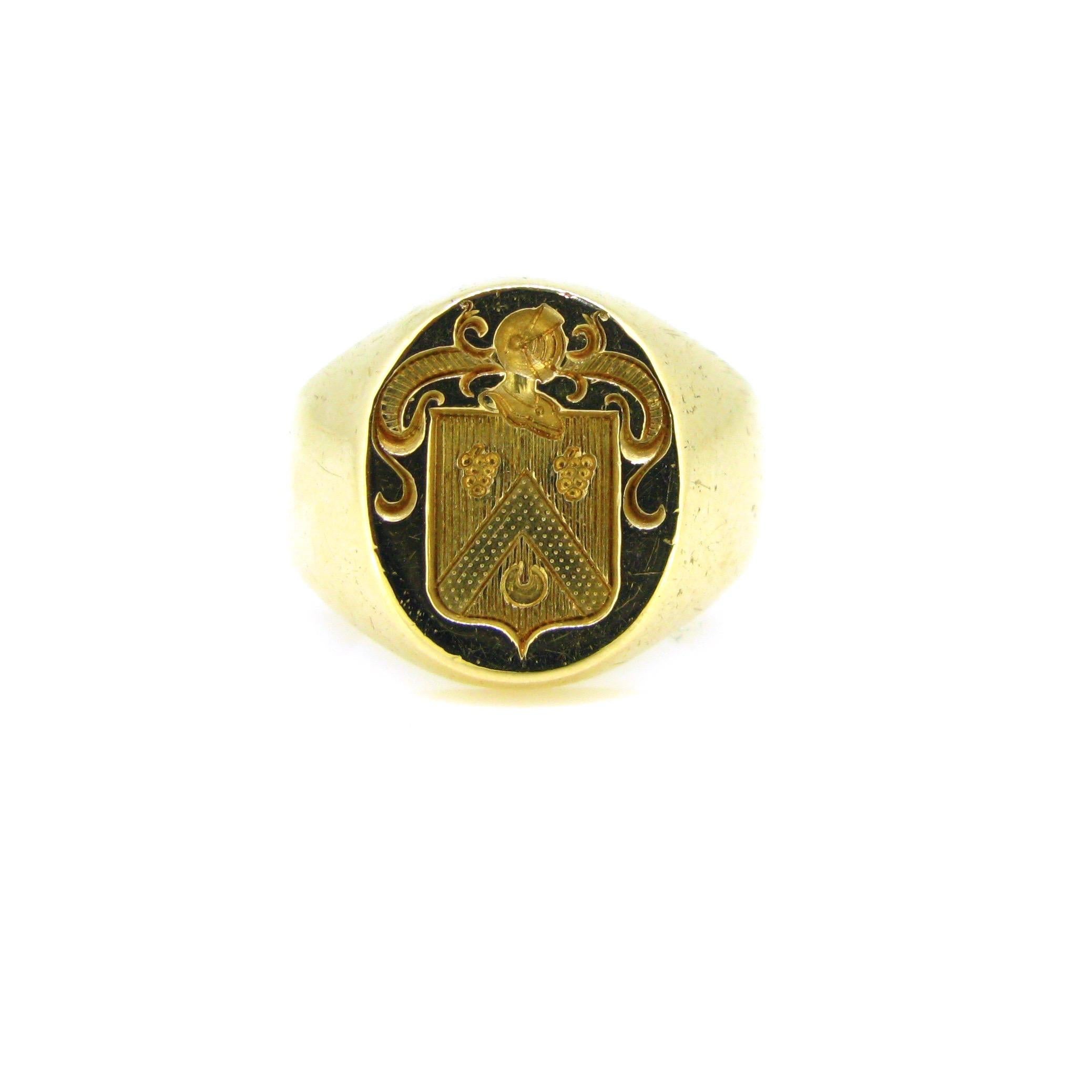  This vintage family crest ring is in very good vintage condition. It presents few traces of wears however the gold is smooth and shiny. The crest was nicely engraved with 2 grapes and a crescent. The blazon is topped with a knight helmet. The ring