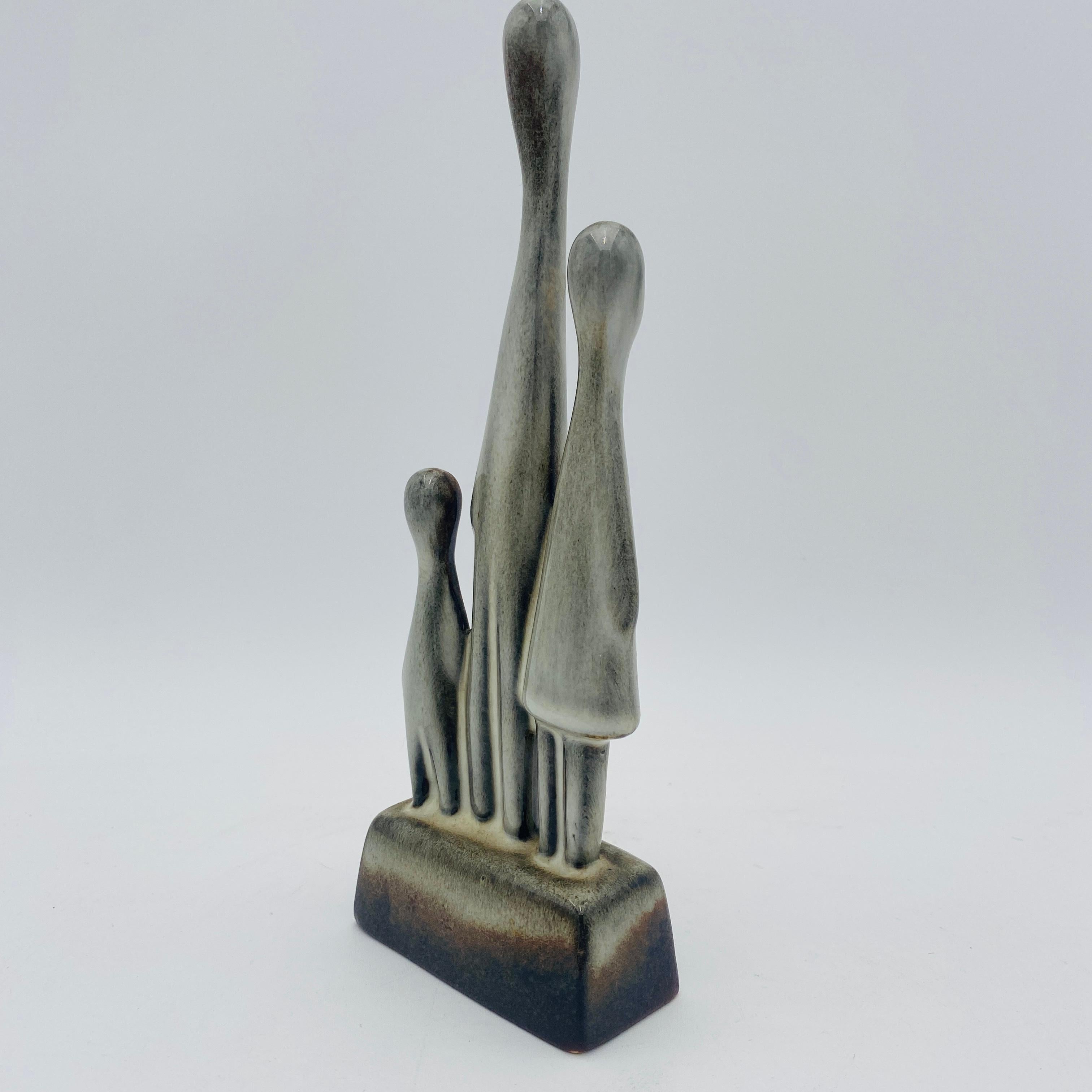 Familia de tres figuras de cerámica esculpidas por Howard Pierce. Howard Pierce se graduó en el Instituto de Arte de Chicago, y más tarde se trasladó a California, donde asistió al Pomona College. Esmalte blanco brillante y acabado marrón. Esta