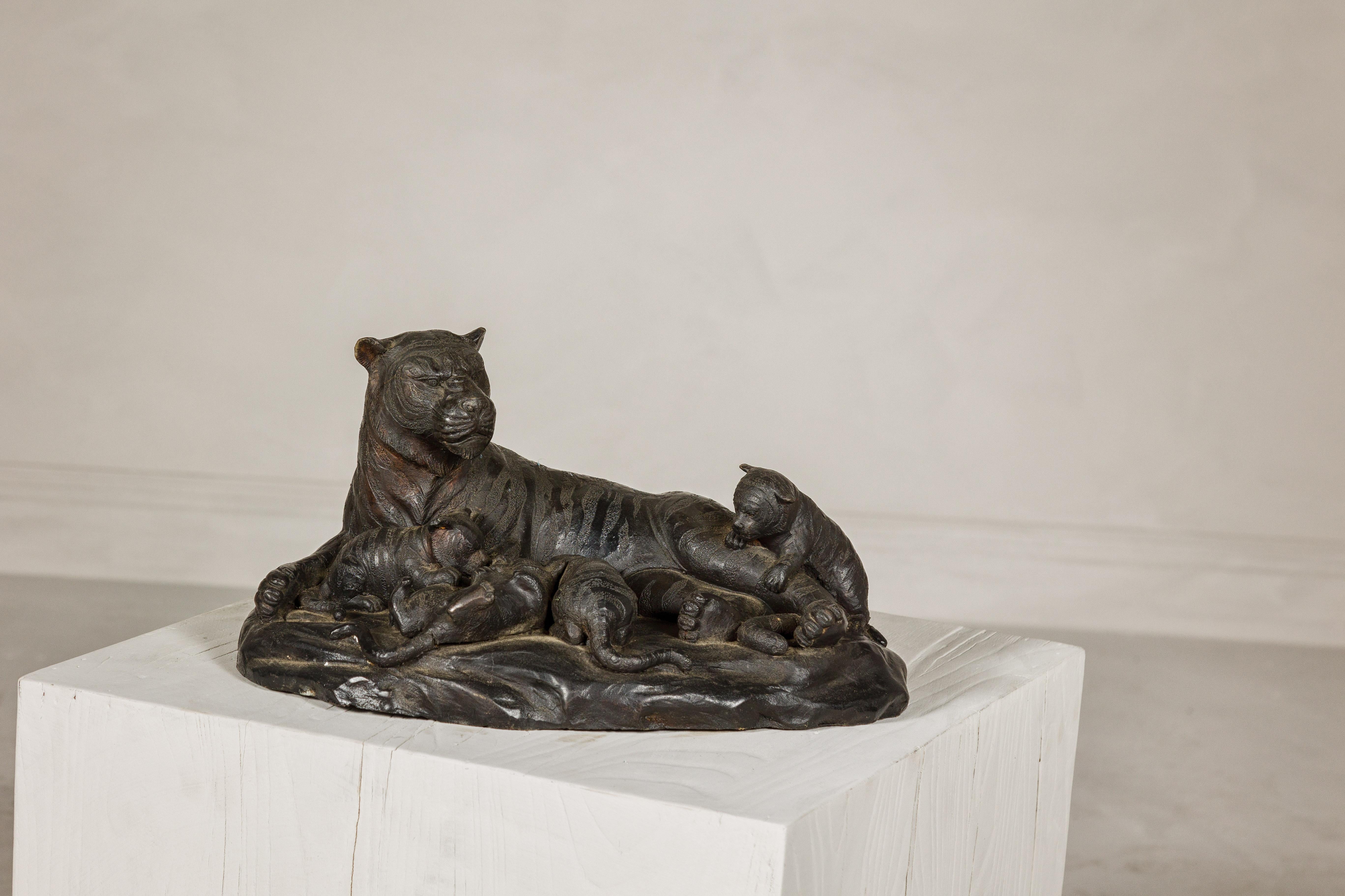 This vintage family of tigers bronze tabletop statuette captures a tender yet powerful moment in the wild, portraying a mama tiger reclining while her cubs playfully crawl over her. The scene is brought to life through the lost wax process, a method
