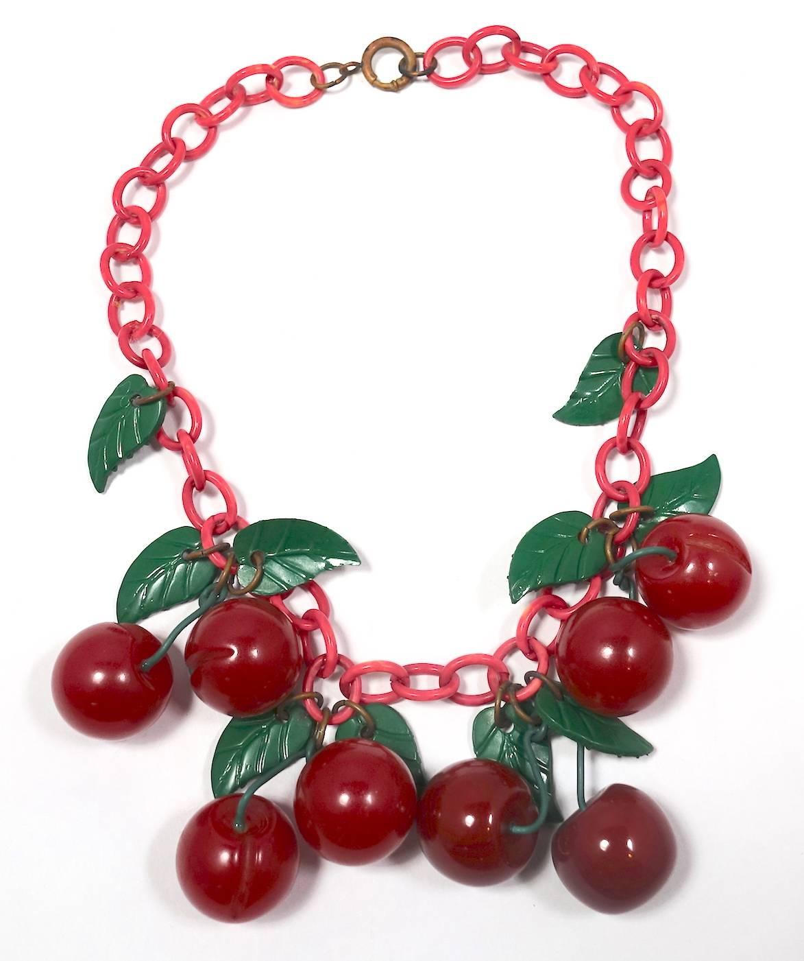 This is the famous 1930s dimpled cherry necklace consisting of 8 carved Bakelite cherries and leaves on a red celluloid open link chain with a spring closure.  In excellent condition, this collectible piece measures 16-1/2” long and the chain width