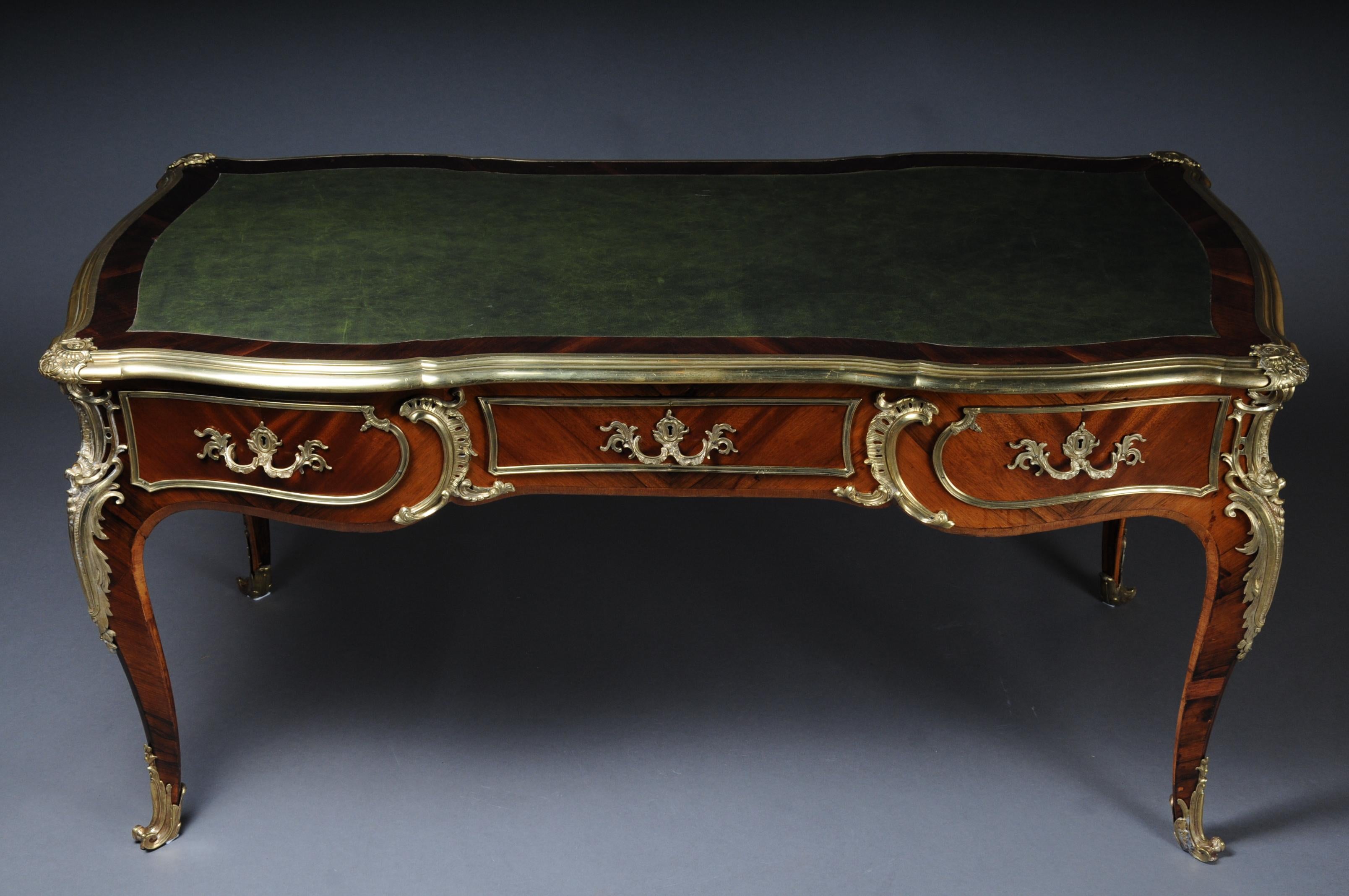 Famous French bureau plat or desk Napoleon III, circa 1870

In Bois Satiné veneer, mirror veneer covering all sides with rocaille applications. Edged with extremely finely chiselled, extremely decorative, restrained bronze fittings. Tulip veneer