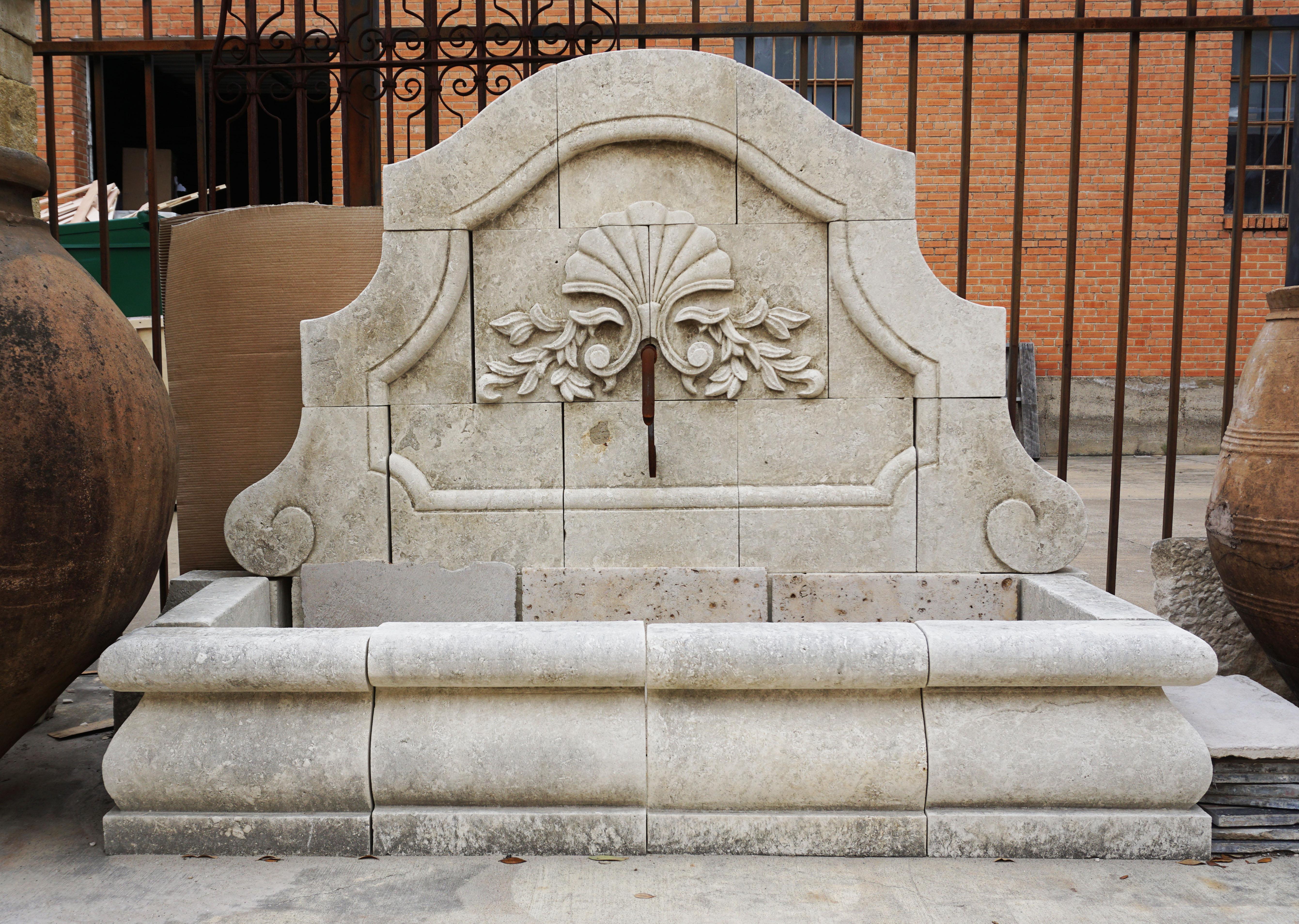 Narrow hand carved limestone wall fountain with fan floral motif and scroll decor

Origin: France

Measurements: 64