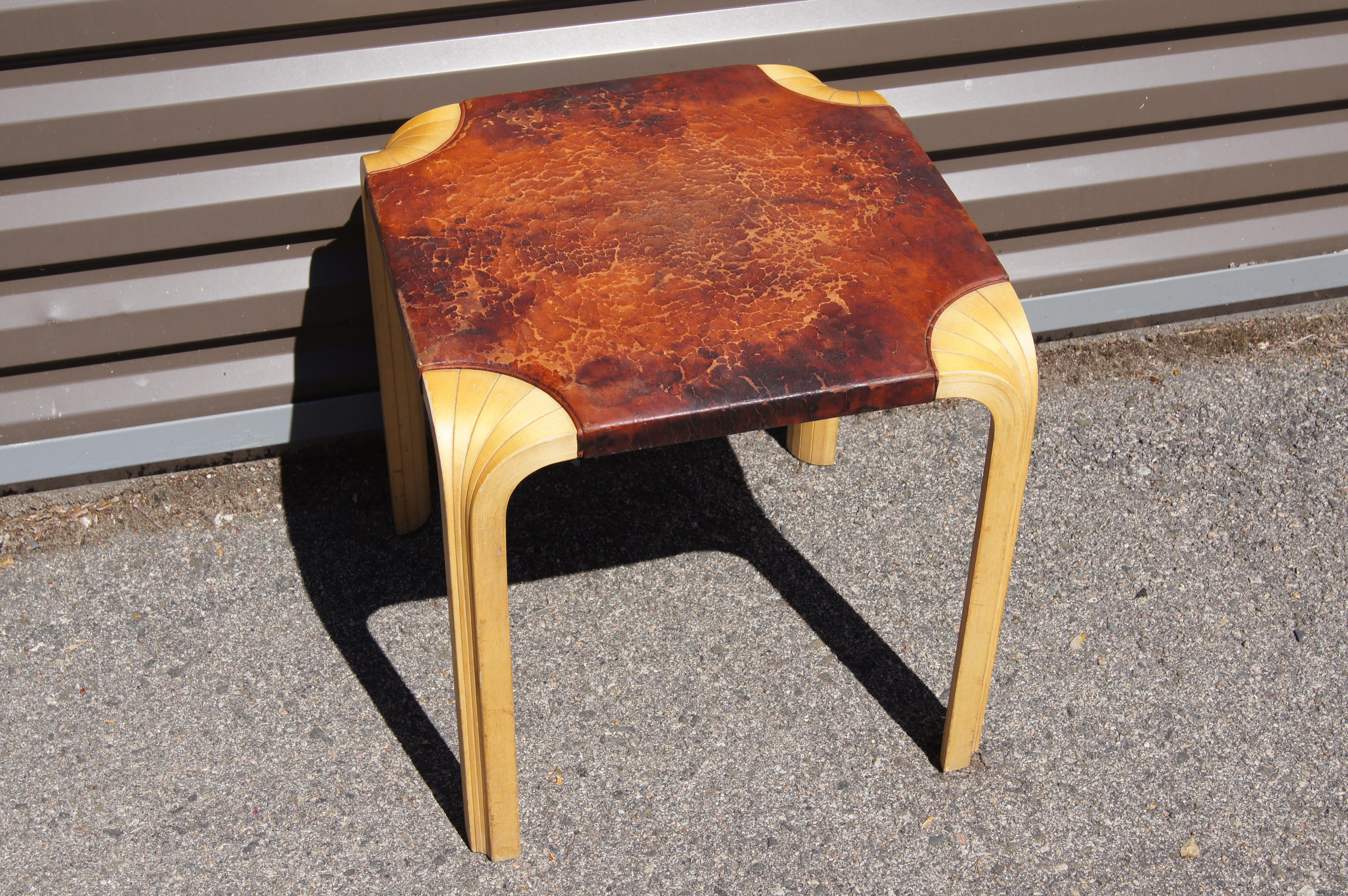 eatures a distinctive five-section fan of bent birchwood, whose joins cascade down the legs, and the original leather-wrapped top with a beautiful patina. The piece can serve as a side or occasional table or as a stool.

Maker's label on underside.