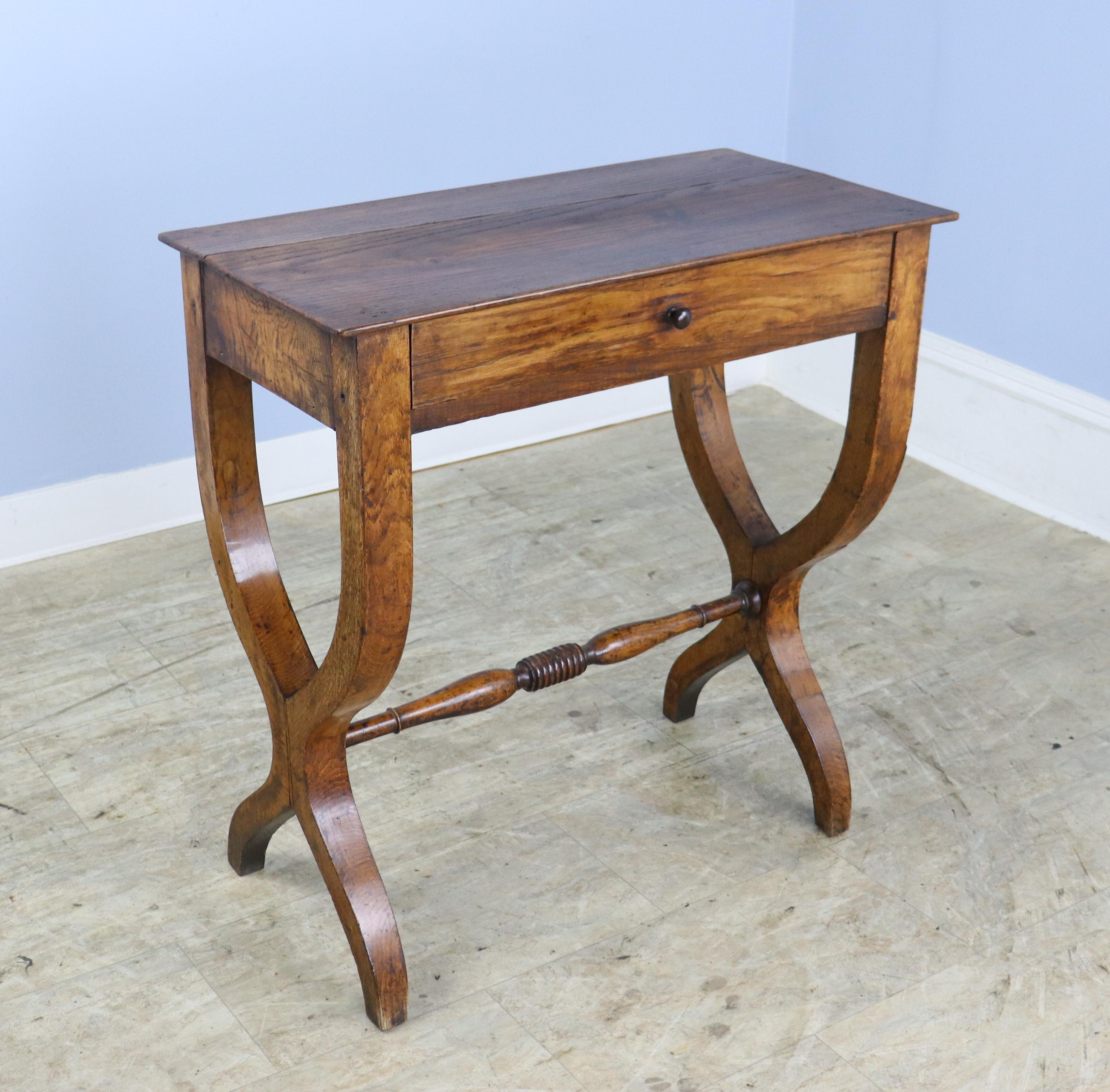 A charming sabre-legged chestnut side table with a single drawer and small wooden knob. Vivid chestnut grain and an unusual shape give this end or lamp table lots of visual impact.