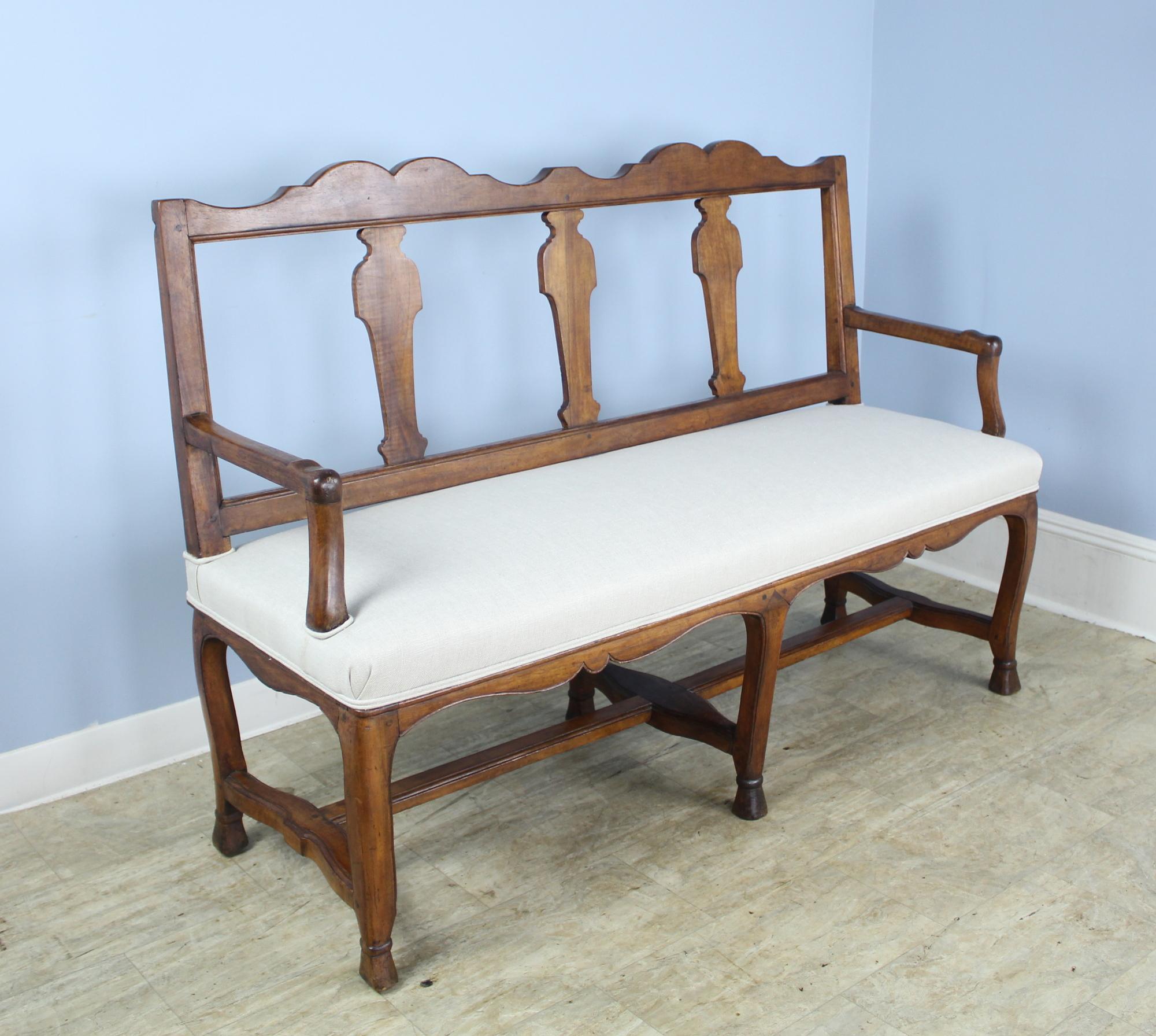 An antique sofa from France in warm mid-range walnut. The high, open back and curved arms and supports are simple and elegant. Lovely shaped apron below the seat and well-shaped hoof feet. Nice comfortable, measures: seat height of 20.25 inches.