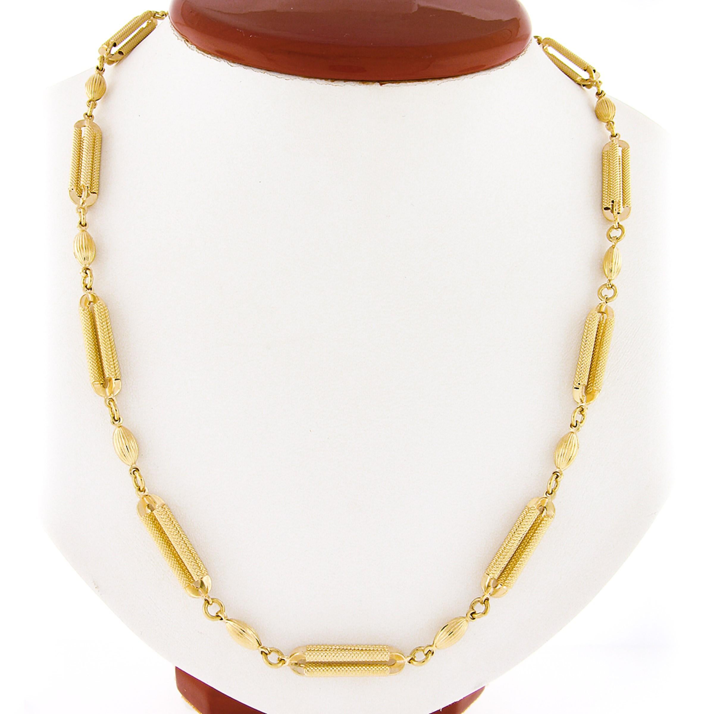 This fancy chain necklace is well crafted in solid 14k yellow gold and features a beautiful design that alternates with unique, open, textured bar links and grooved oval beads throughout. The textured links look absolutely wonderful next to the
