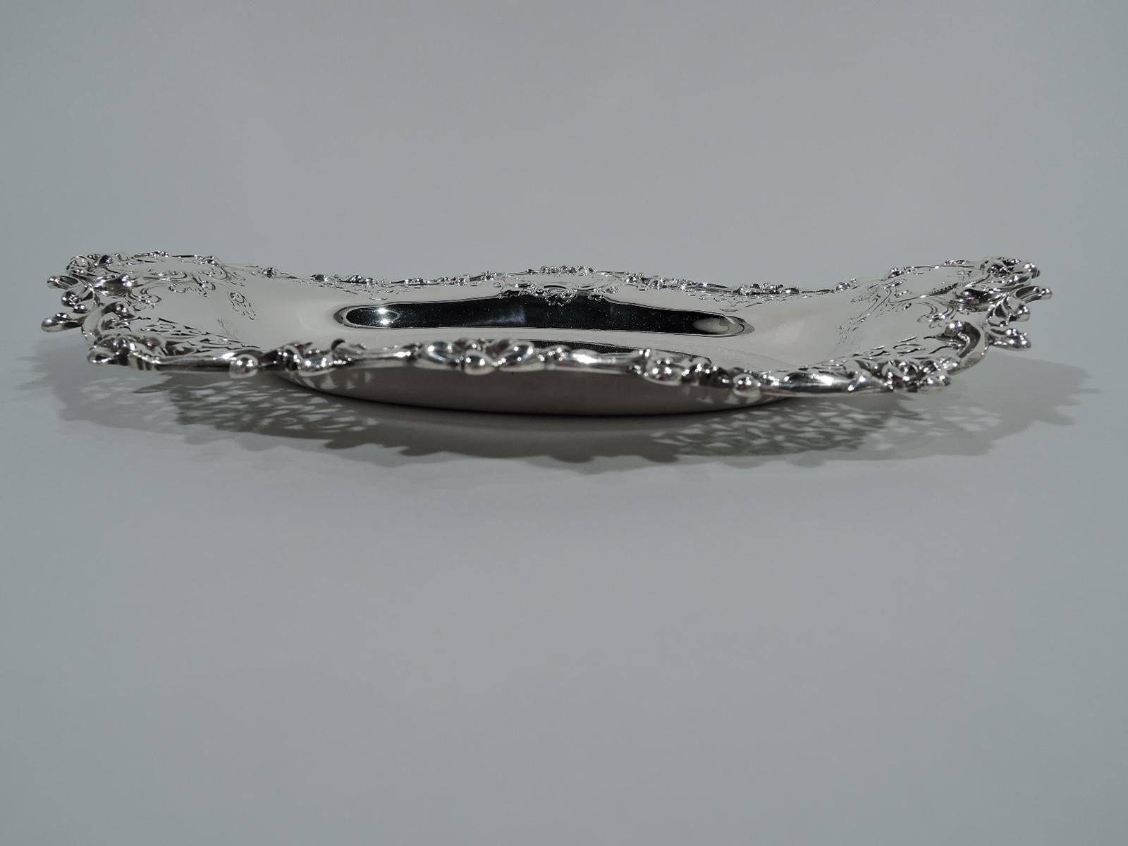 Fancy sterling silver serving dish. Made by Howard & Co. in New York in 1892. Oval well and wavy scrolled rim chased and applied scrolls and flowers and pierced scrollwork. Scrolled frames (vacant). Hallmark includes year. Heavy weight: 18.6 troy