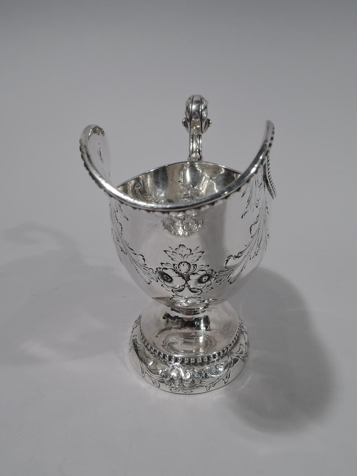 Fancy coin silver gravy boat. Made by Bailey & Co. in Philadelphia, circa 1860. Helmet form with leaf-capped flying scroll handle and domed oval foot. Chased flower-and-leaf garlands and bold beading. A great midcentury piece by a historic maker.