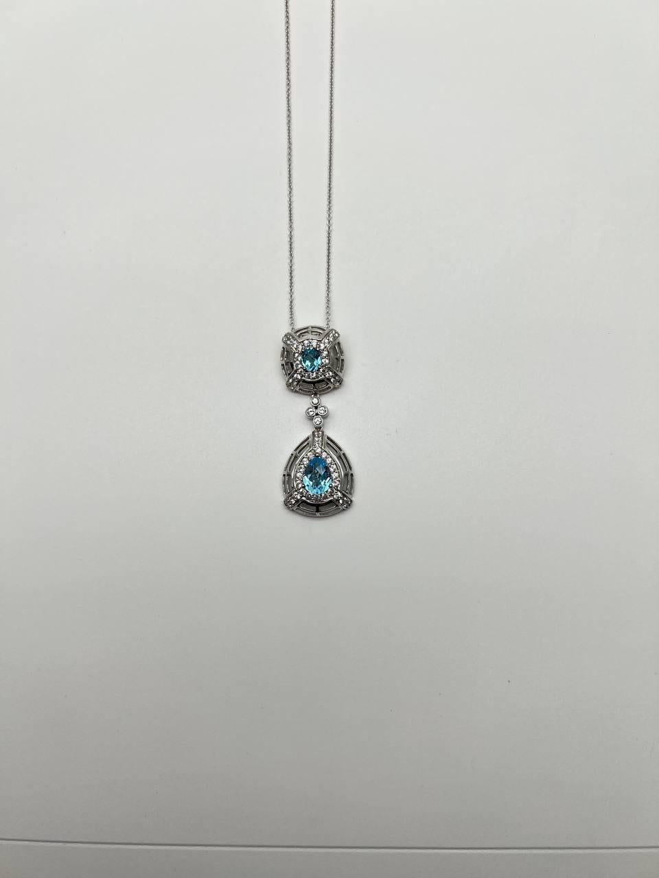 Elegant Pendant Necklace with Blue Topaz and Diamond Accents. This exquisite necklace features a delicate chain crafted in a lustrous metal. The pendant showcases two stunning blue topaz stones, each surrounded by a halo of sparkling diamonds. The