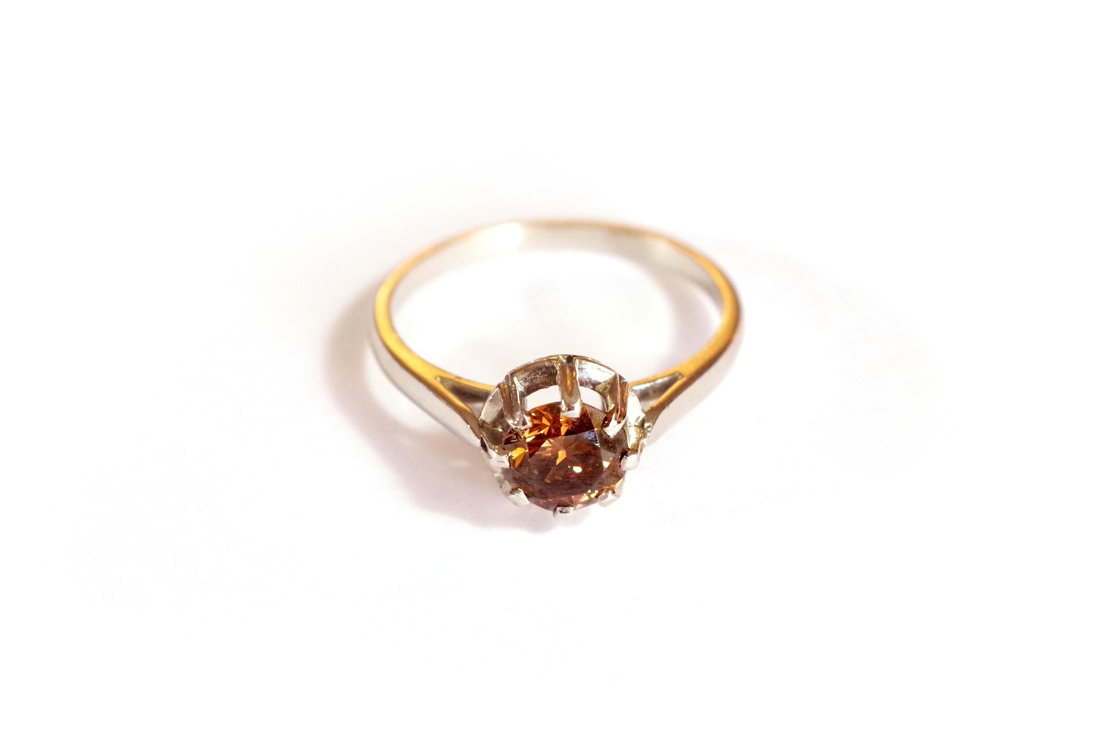 Fancy brown diamond ring: a solitaire diamond fancy cognac ring in platinum. This ring is centered on a magnificent brilliant cut fancy diamond, whose brown color sparkles with orange. The diamond weighs 0.79 carat and is set with 8 claws. Antique