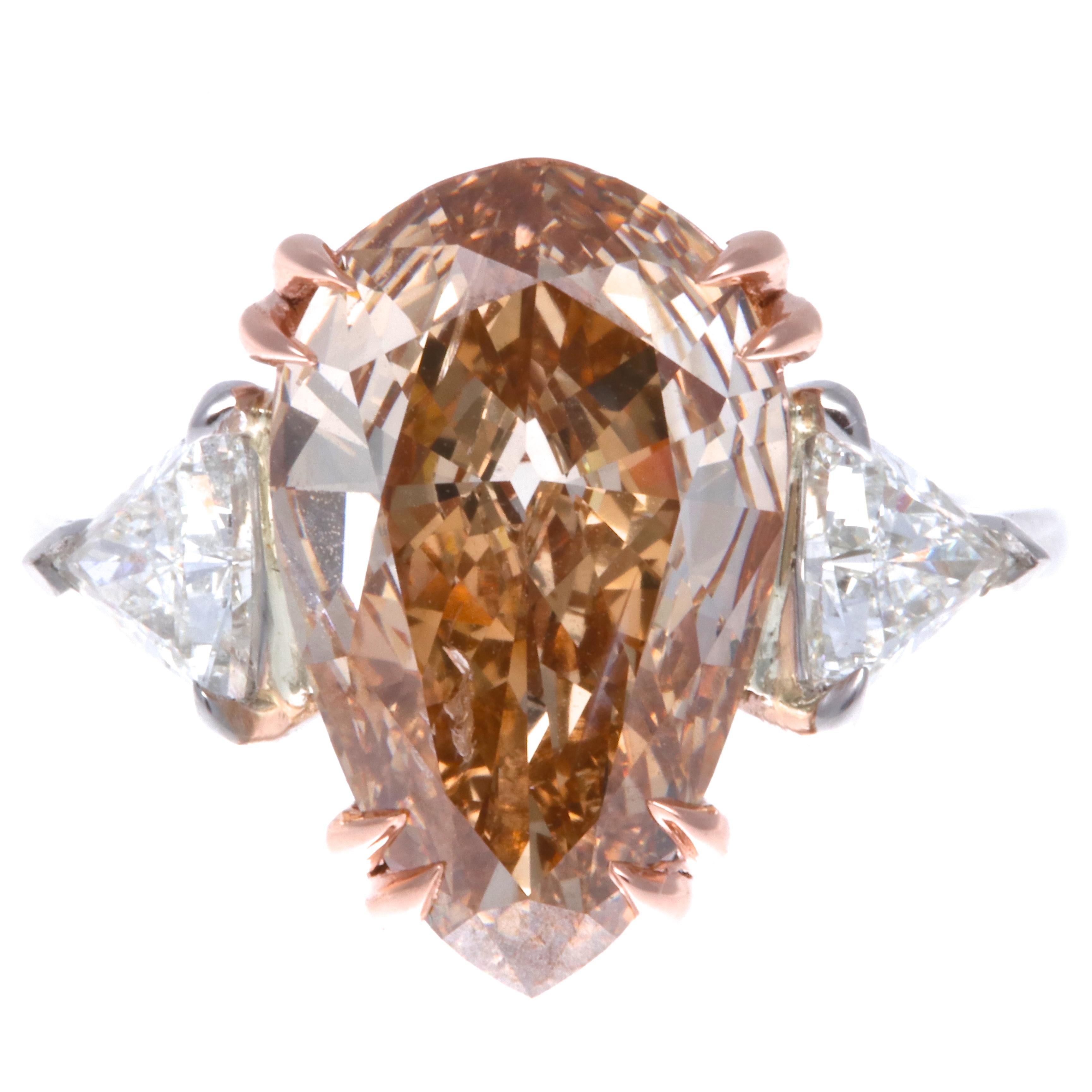 An engagement ring that no one else has! This one of a kind modern diamond platinum ring features a GIA certified fancy orange-brown pear shape diamond 4.37 carats set in rose gold.  Flanked by two trillion cut diamonds, 0.75 carats G,H color VS2