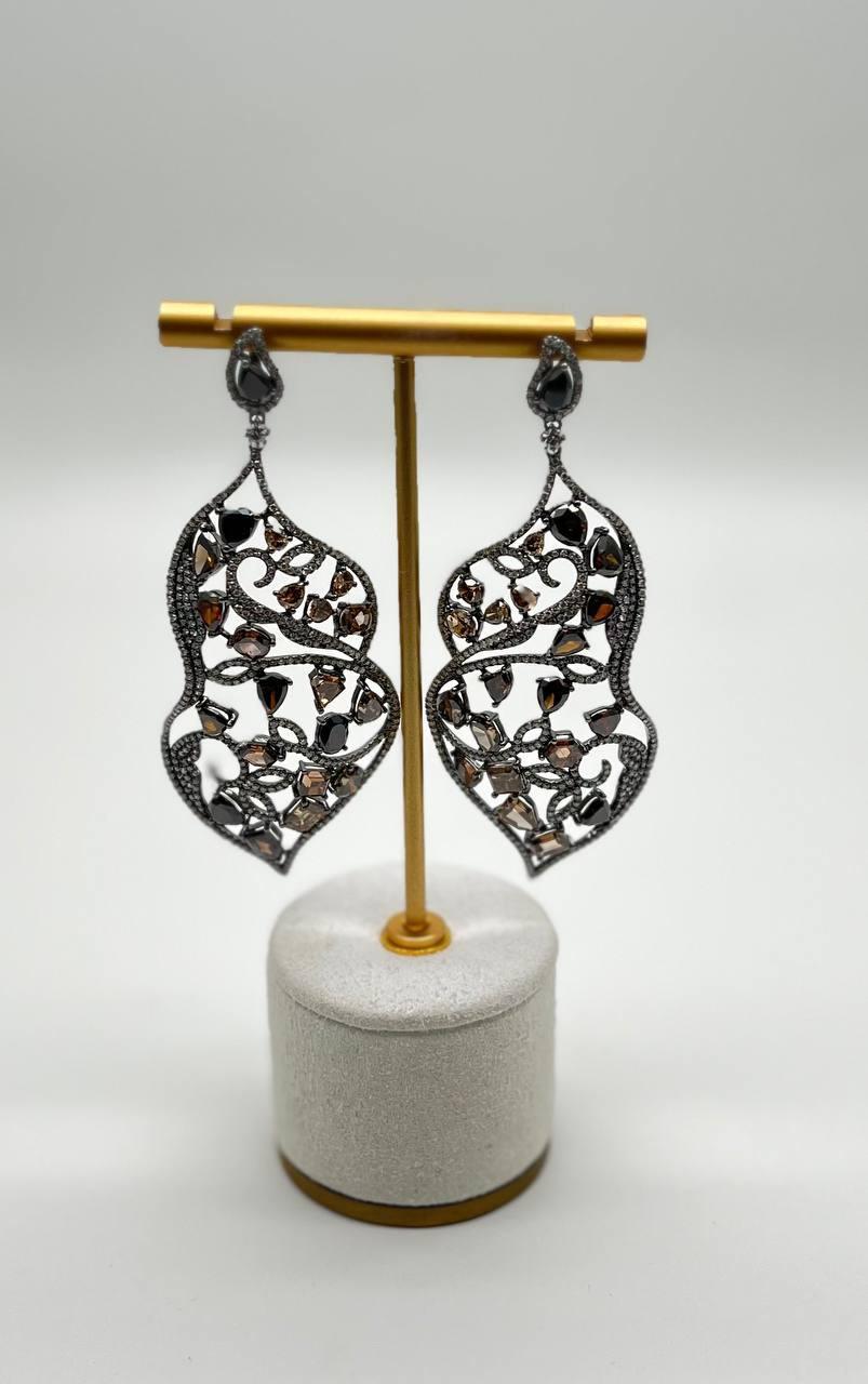 These striking earrings are crafted with a combination of 18k white and black gold.

Each earring features an intricate openwork design, adorned with a variety of fancy color (20.20 ctw) and white diamonds (4.24 ctw) in different shapes and
